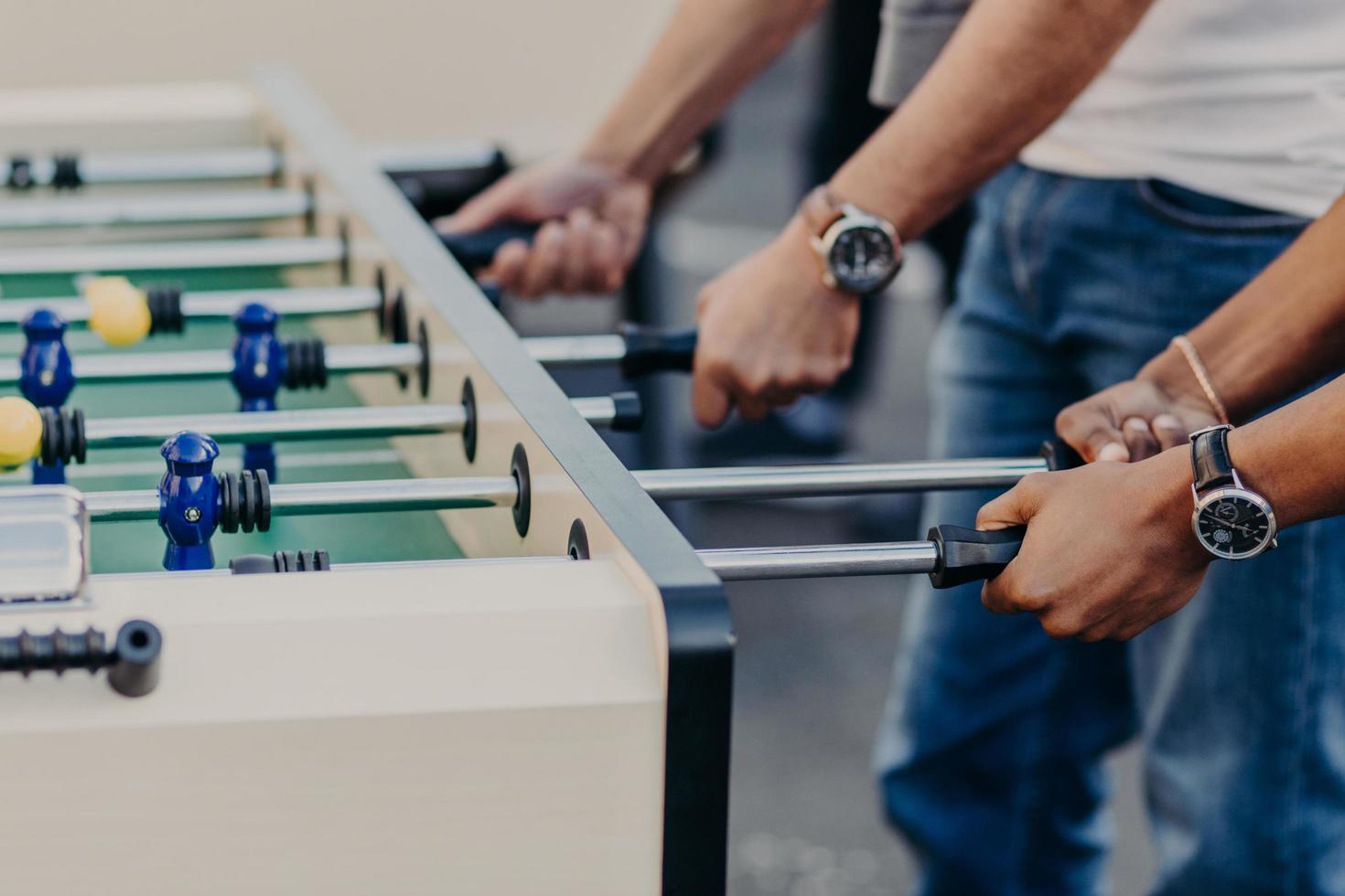 Table football game or soccer. Men play kricker together during weekend as have spare time, enjoy recreation time. Heated people. photo