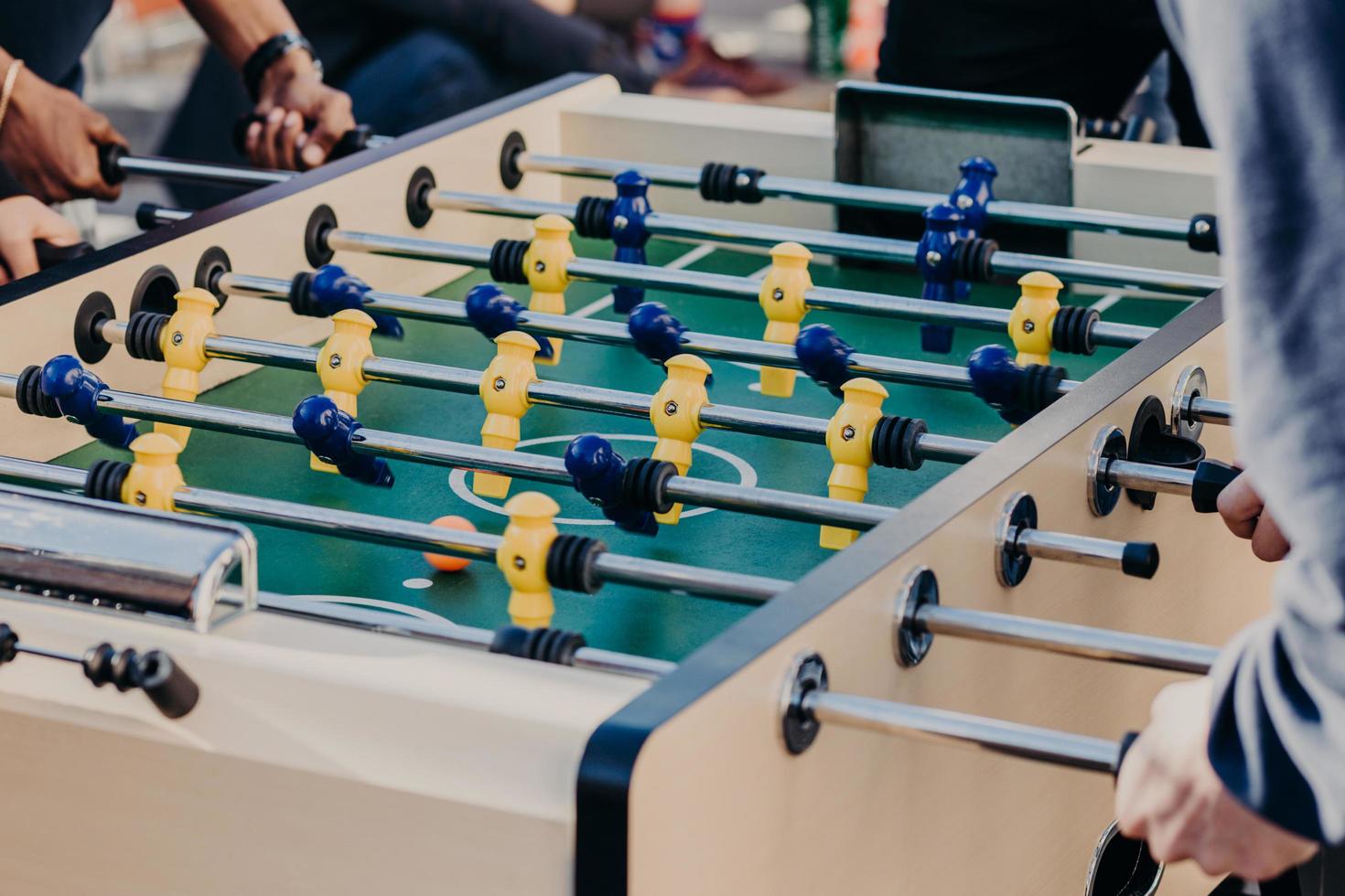 los amigos juegan al futbolín, pasan el tiempo libre en el centro de entretenimiento. concepto de recreación y ocio. jugadores activos. juegos de deporte foto