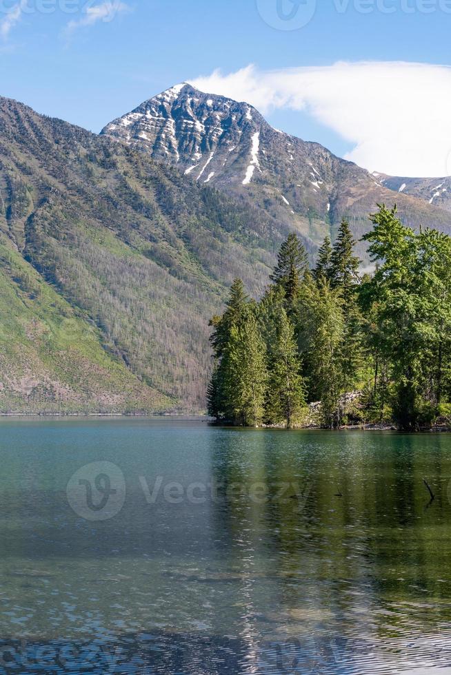 una imagen vertical del bosque y el pico de una montaña a lo largo de la orilla del lago mcdonald en el parque nacional de los glaciares, montana. foto