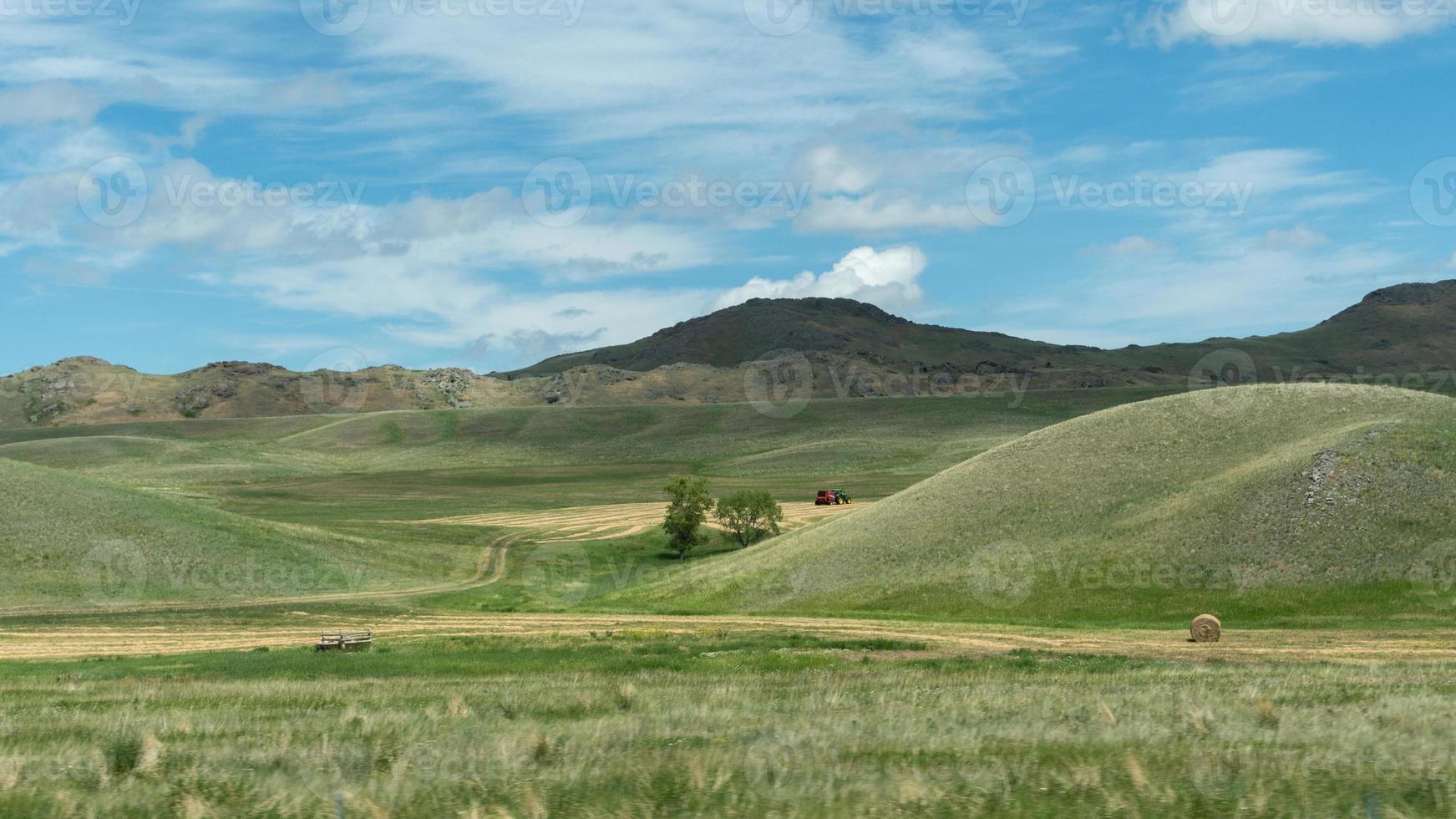 un tractor trabajando en las ondulantes colinas verdes del oeste de montana. foto