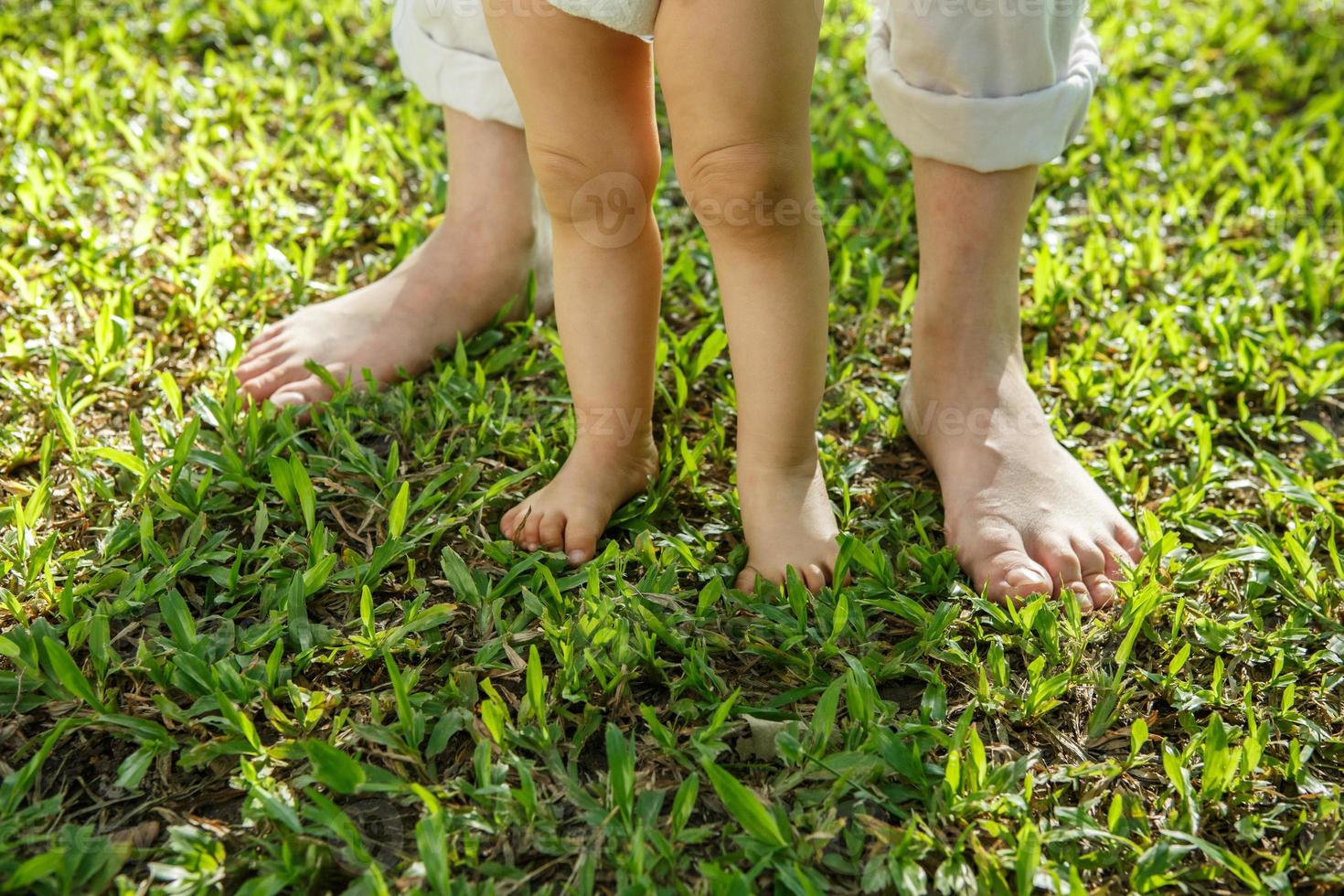 Closeup portrait of a mother helping baby to walk on grass photo