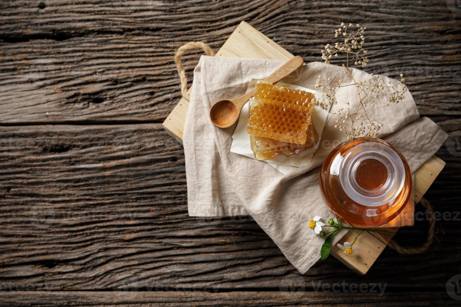 abeja de miel en tarro y panal con cucharón de miel y flor en mesa de madera, productos de abeja por concepto de ingredientes naturales orgánicos, espacio de copia para su texto foto