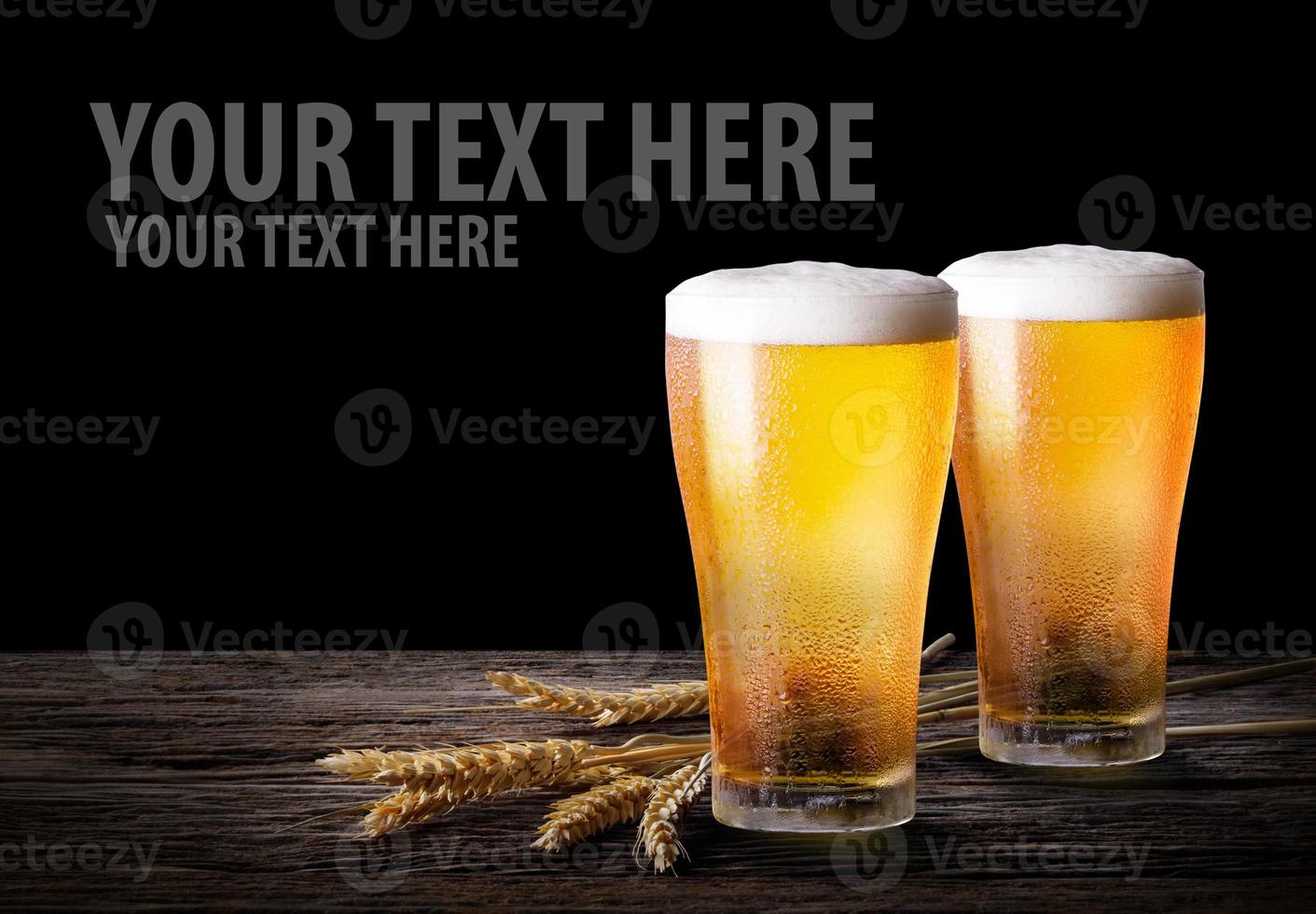 Cold beer with wheat on wooden table. Glasses of light beer on the isolate black  background with copy space. photo