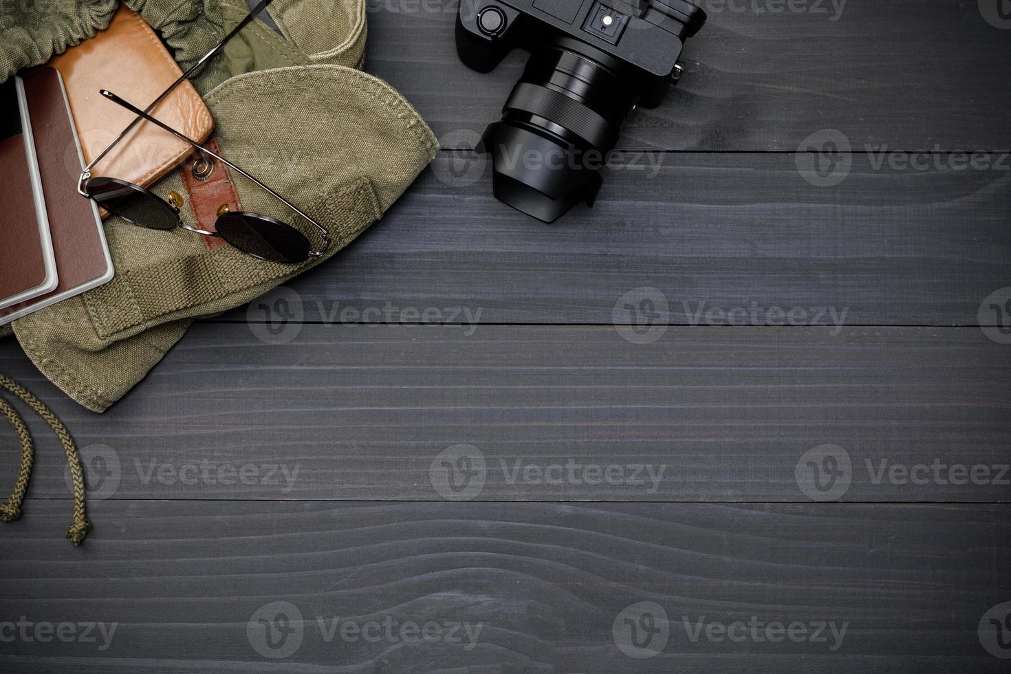 Top view mockup of Traveler's accessories with passport, books of travel plan, wallet, camera and backpack on black wooden desk empty space, Travel concept background photo