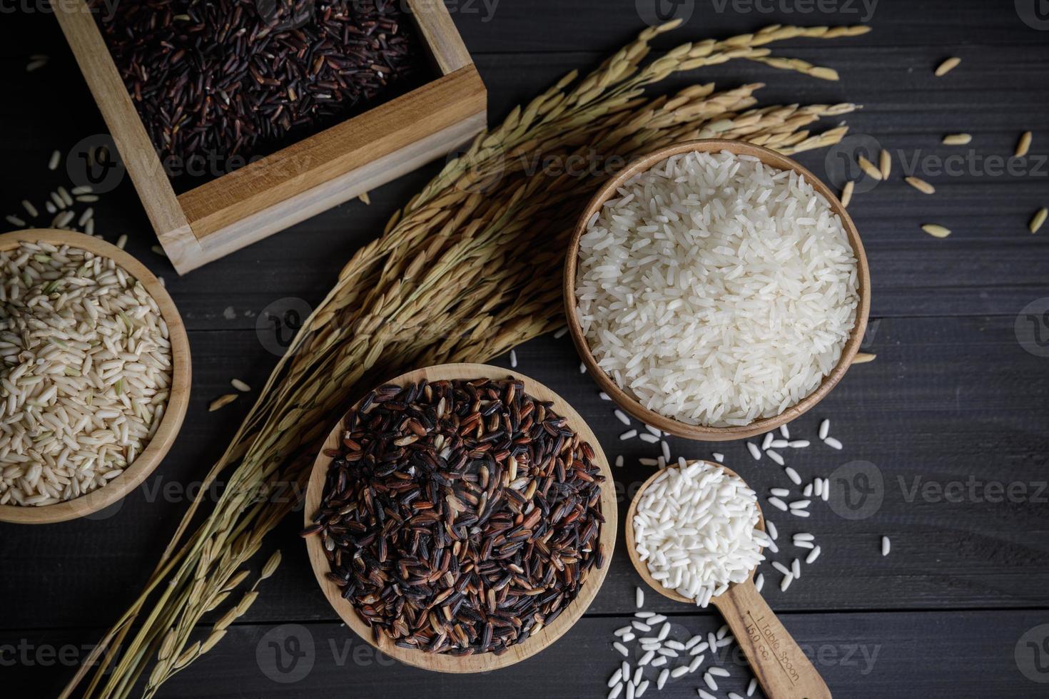 arroz japonés con arroz jazmín tailandés y semillas de arroz con cáscara en una mesa de madera foto