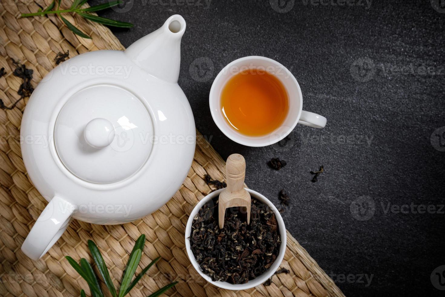 taza de té con jarras humeantes y té seco en la mantelería sobre el fondo del escritorio de piedra negra con espacio de copia para el texto. foto