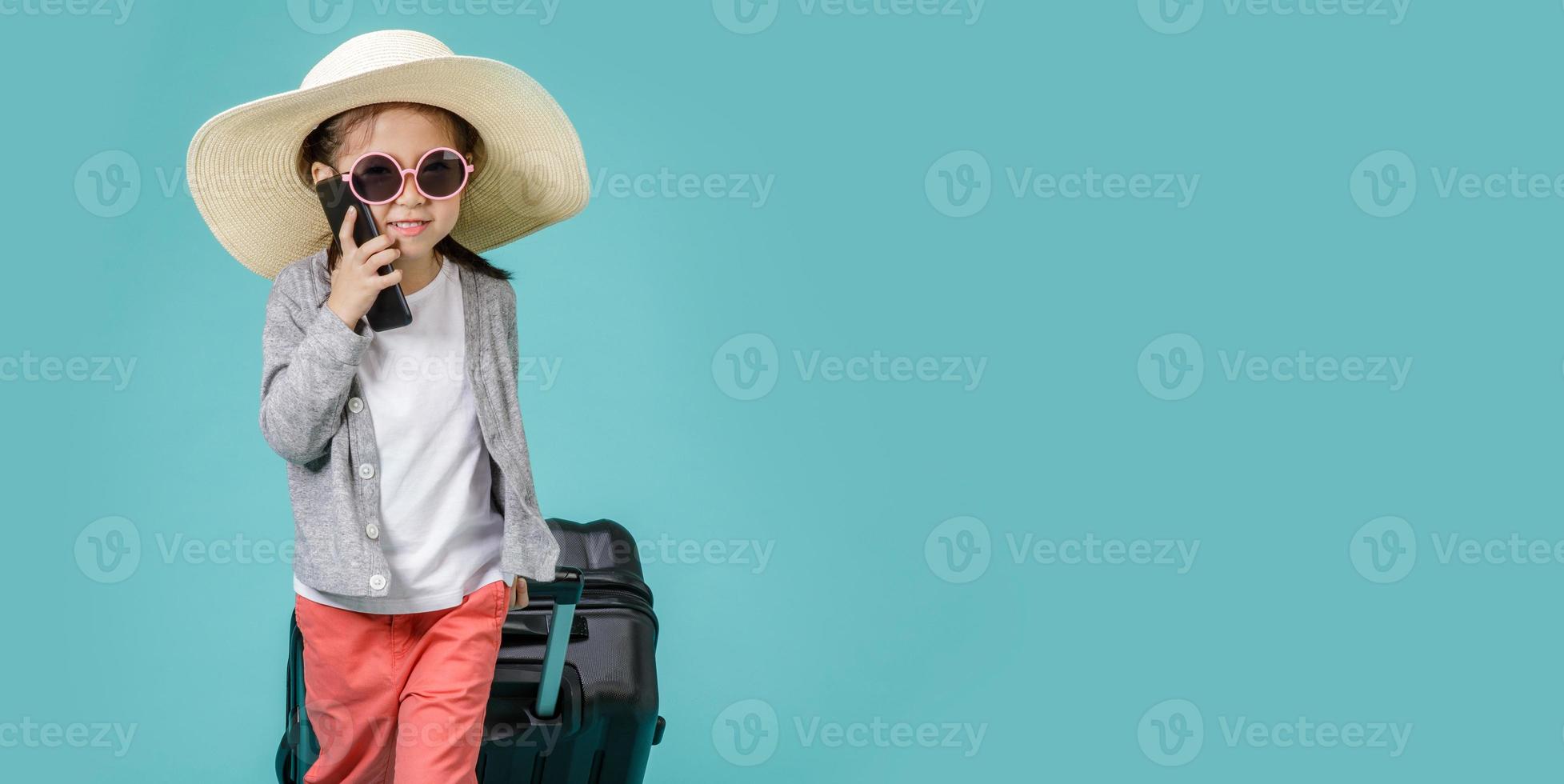 Asian little girl is using a smartphone to check flight to travel on weekends, empty space in studio shot isolated on colorful blue long banner background photo