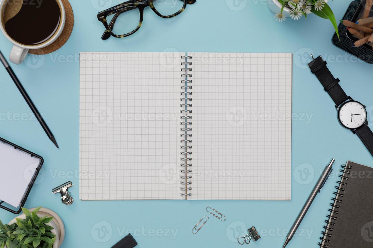 Top view workspace office supplies mockup hot coffee cup, glasses, books and accessories isolated on blue background overhead view with copy space, Workspace for new designer background photo