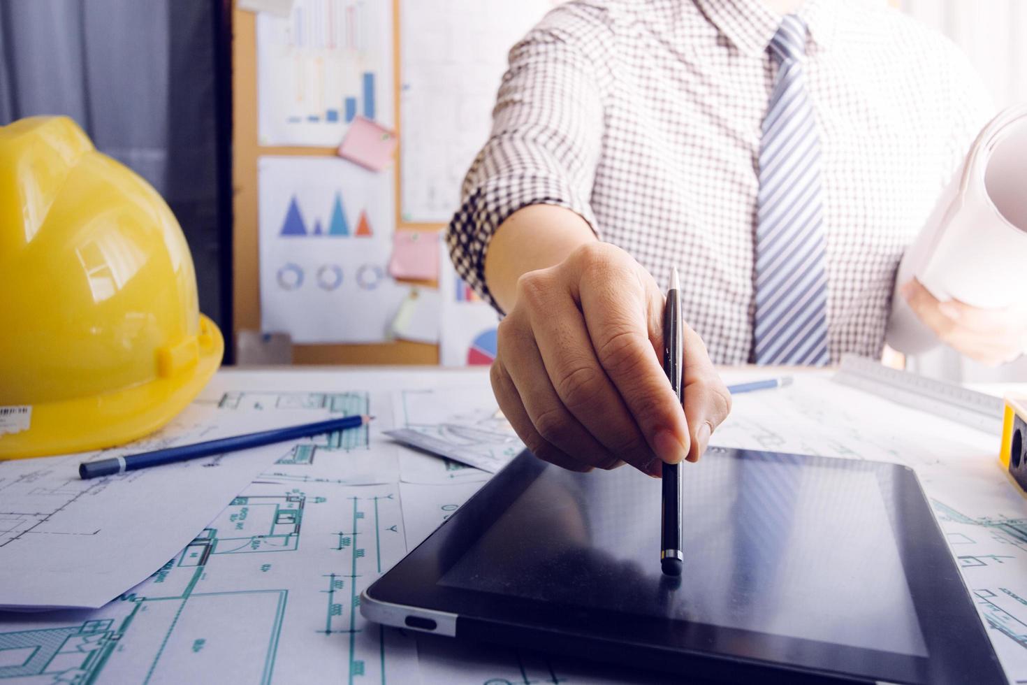 business hand working and laptop with on on architectural project at construction site at office desk in office photo