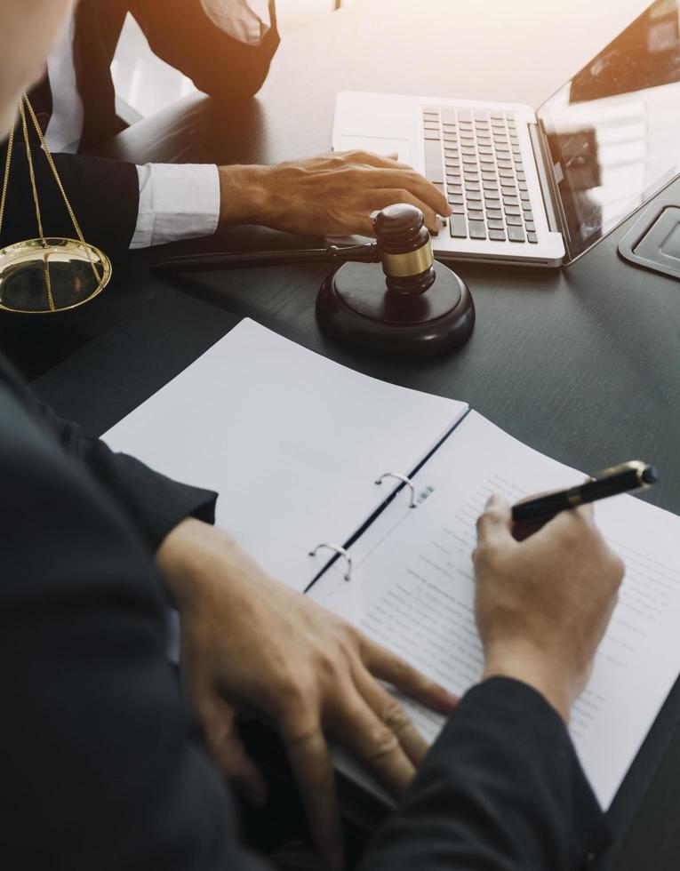 concepto de justicia y derecho. mazo en el bloque de sonido en la mano del juez masculino en una sala del tribunal, trabajando con libros de derecho de documentos, informe el caso sobre la mesa en la oficina moderna. foto