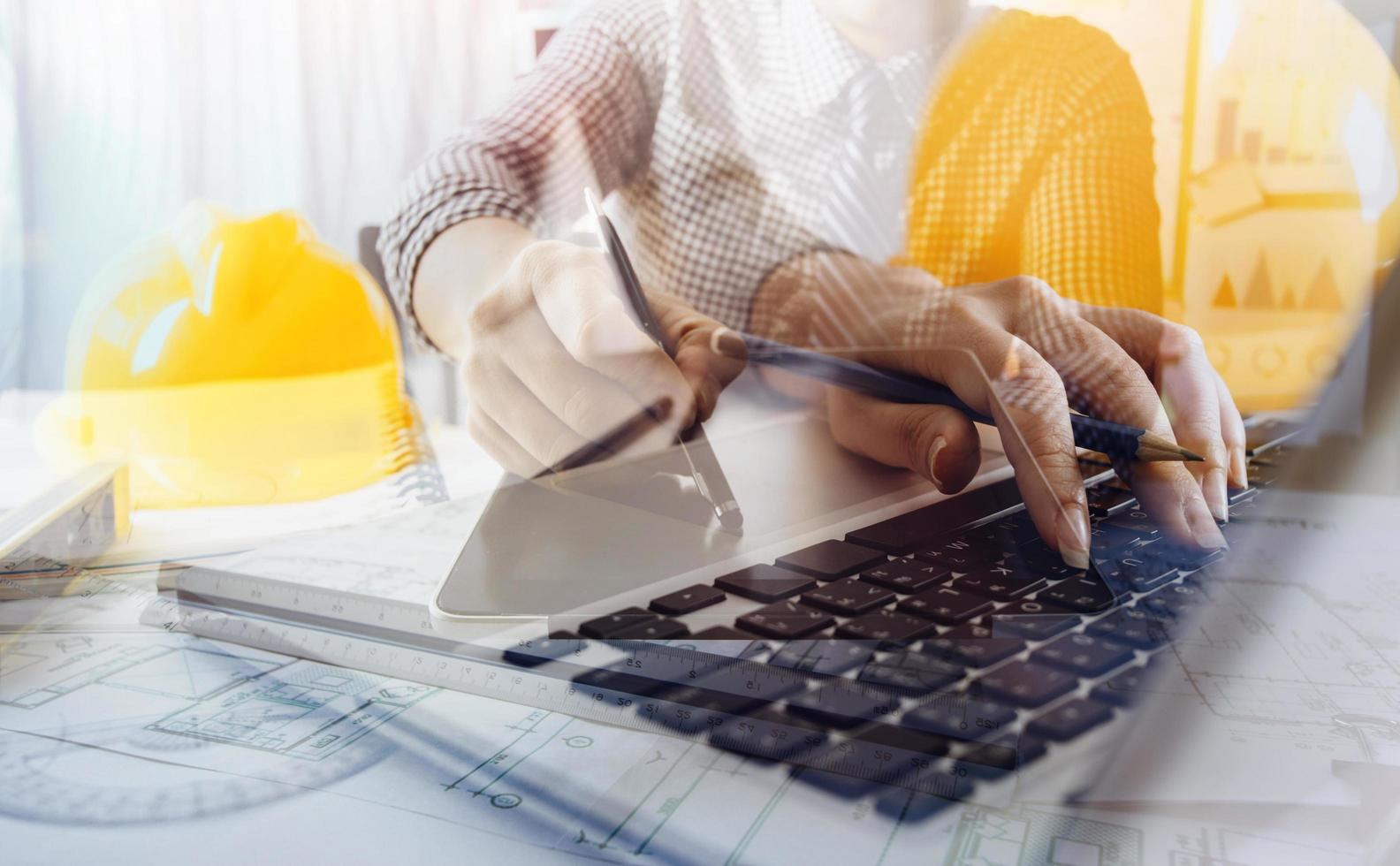 business hand working and laptop with on on architectural project at construction site at office desk in office photo