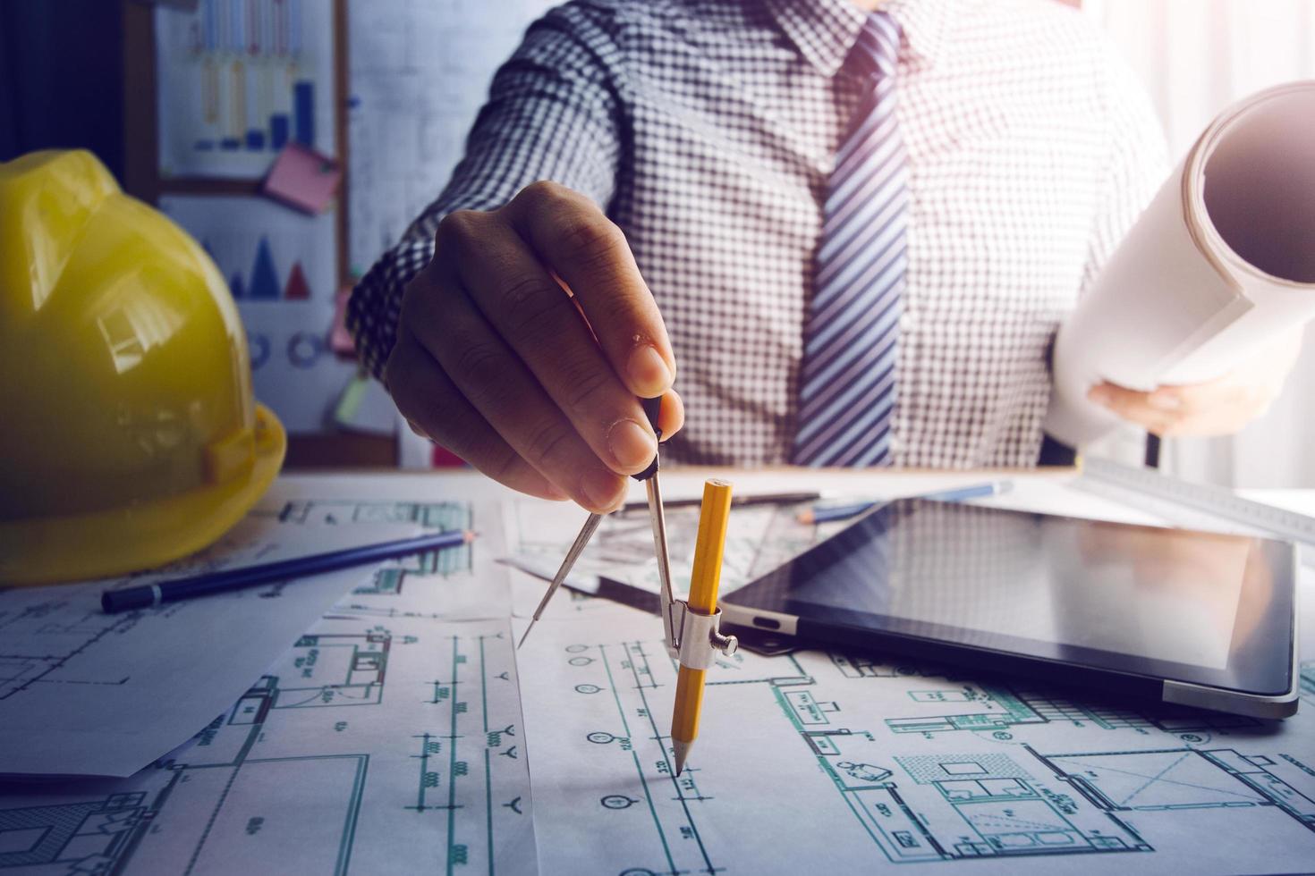 Two colleagues discussing data working and tablet, laptop with on on architectural project at construction site at desk in office photo