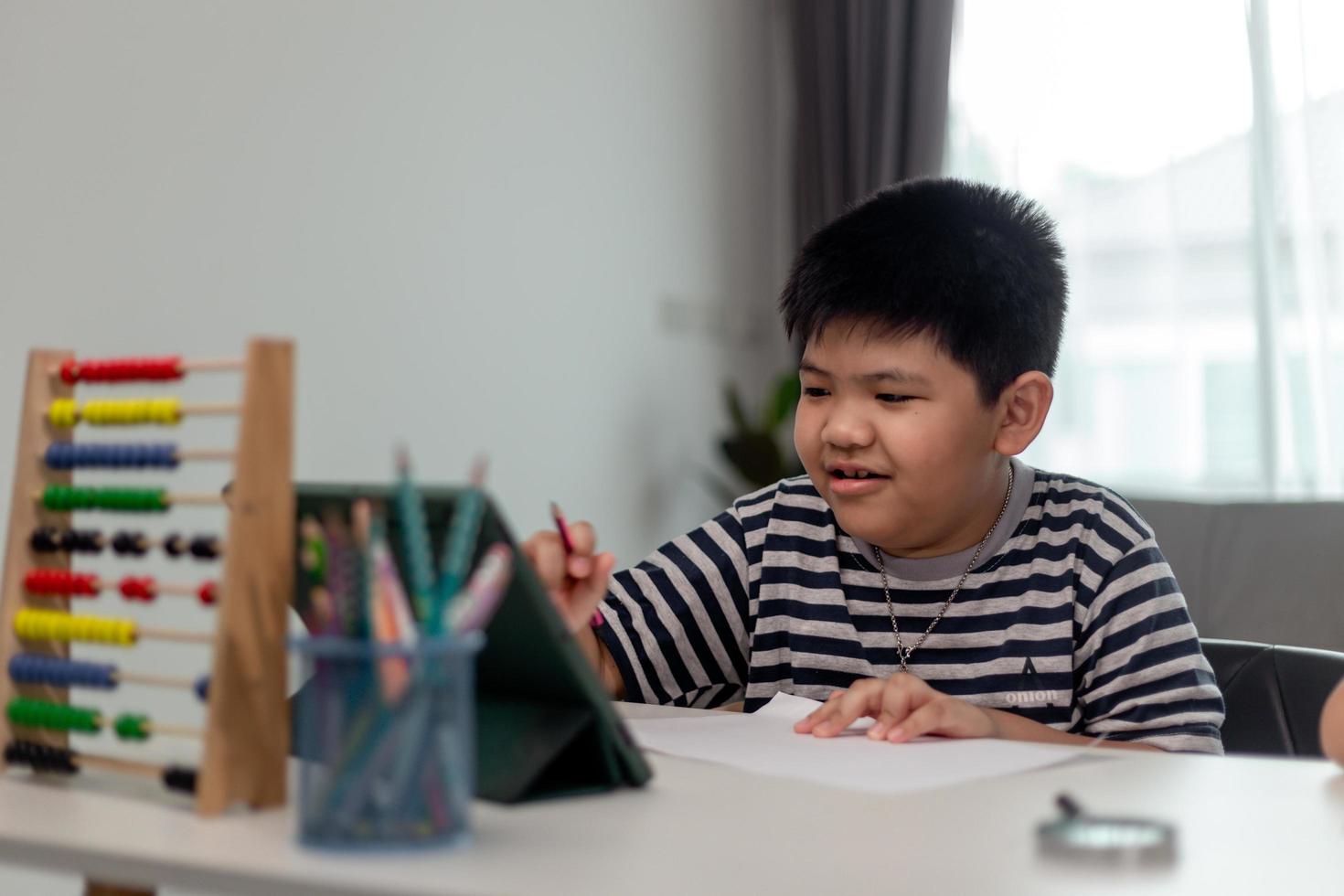 Cute Asian child learning class study online with video call from tablet at home .Social distancing concept photo