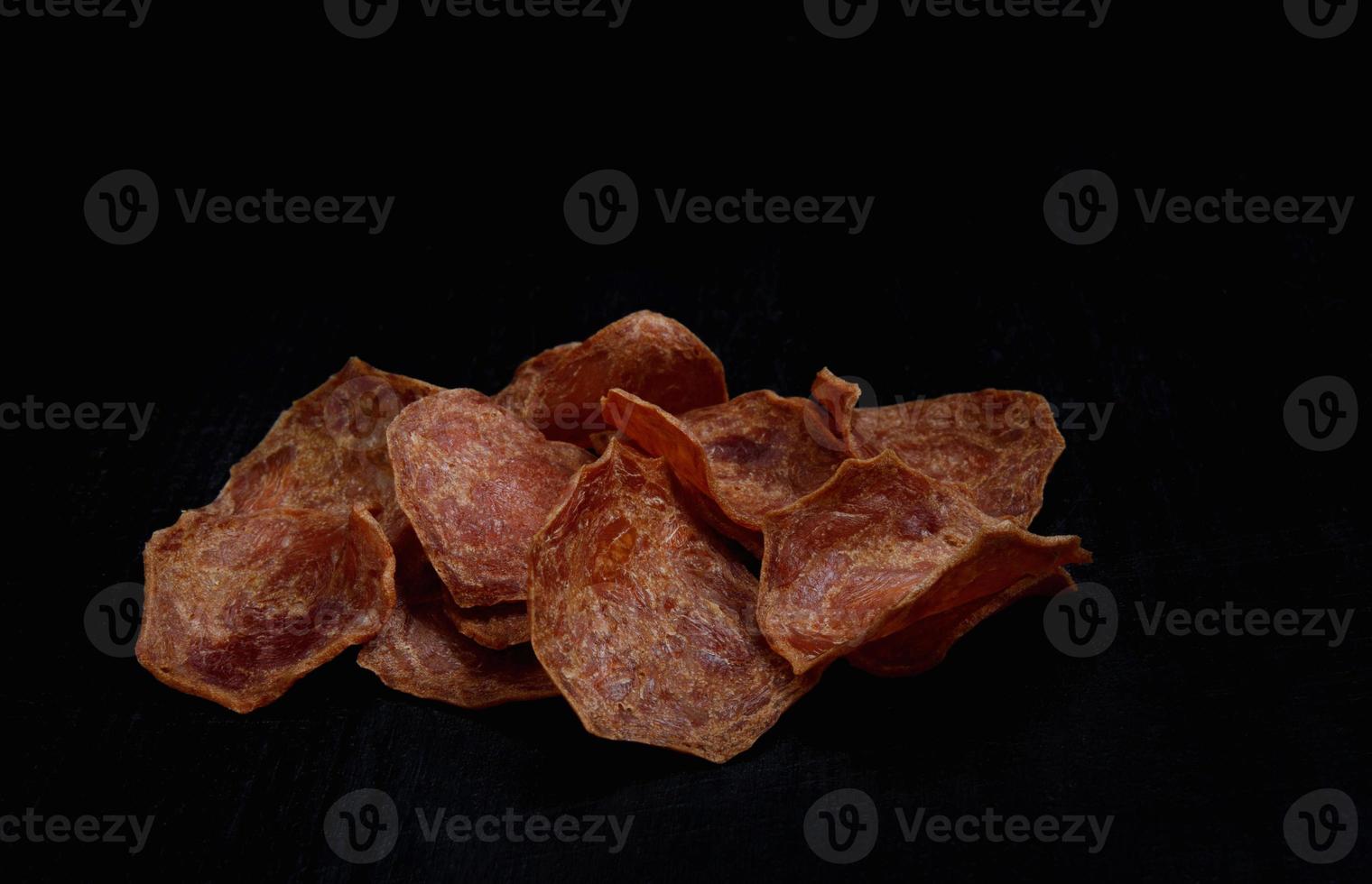 Meat chips on a black background. Beautiful placer of thin slices of dried meat. photo