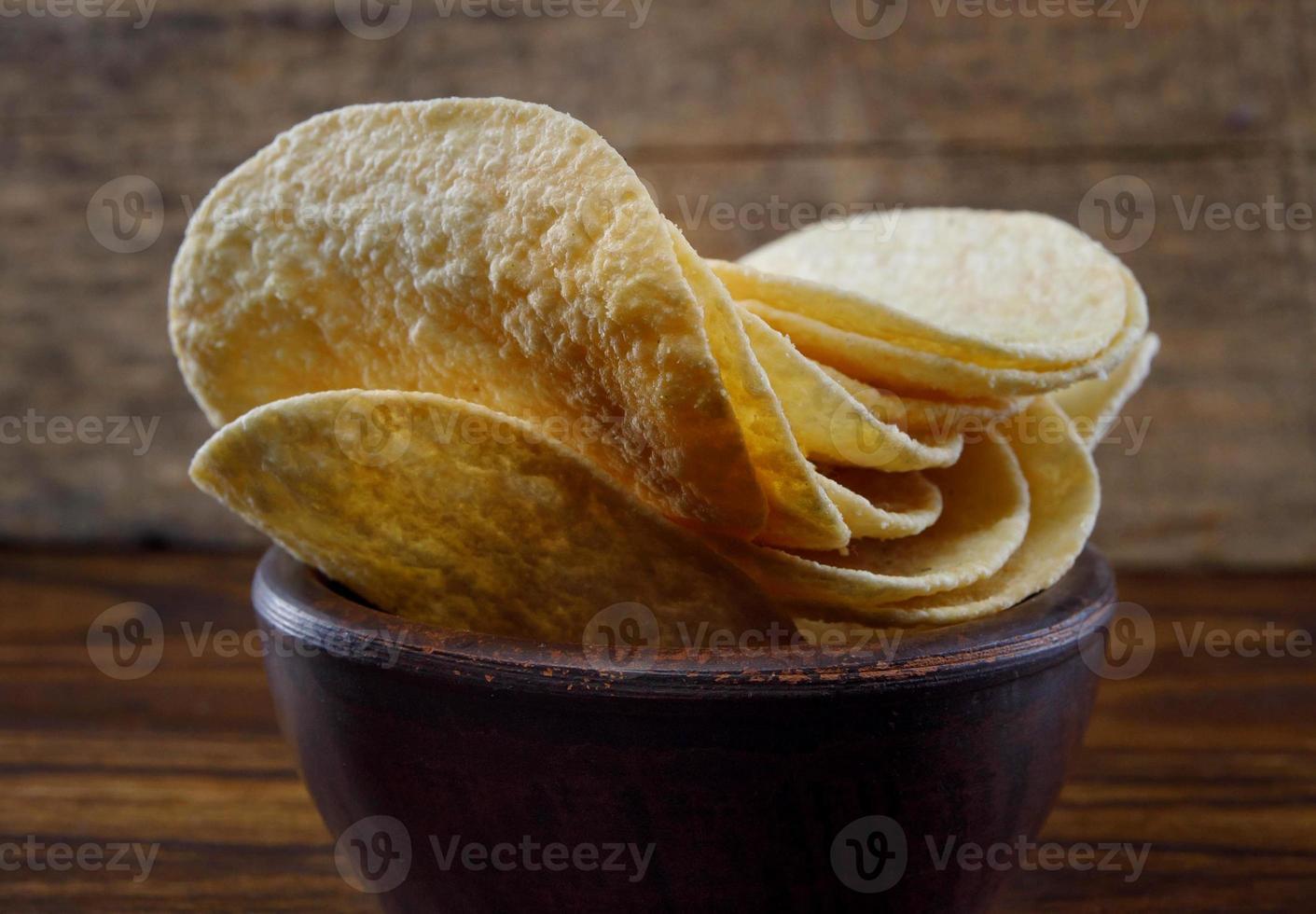 una taza de cerámica con patatas fritas se encuentra en la superficie de la mesa. foto