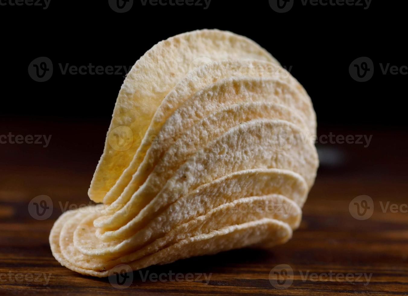 A stack of potato chips lies on a wooden table. photo