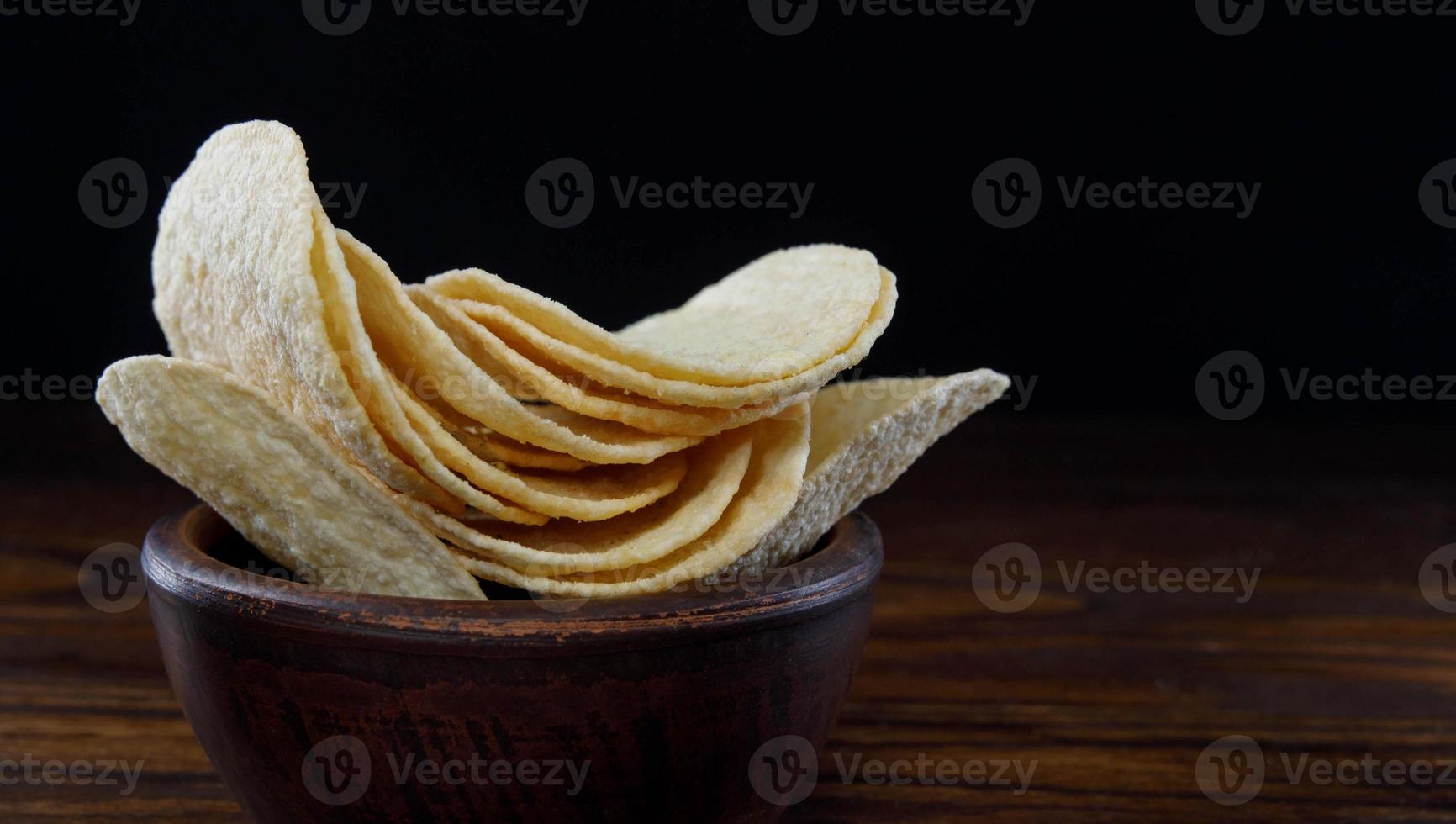 una taza de cerámica con patatas fritas se encuentra en la superficie de la mesa. foto