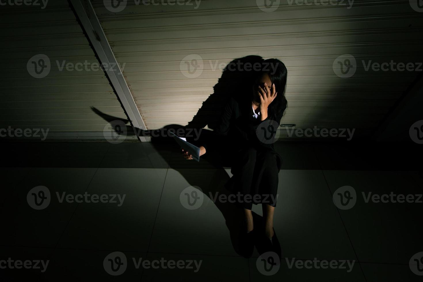 Woman depressed from sad stress pain despair problem, person sit on closed shop on corridor alone with emotion lonely desperate upset head down. Head in hand no way out concept, copy space photo