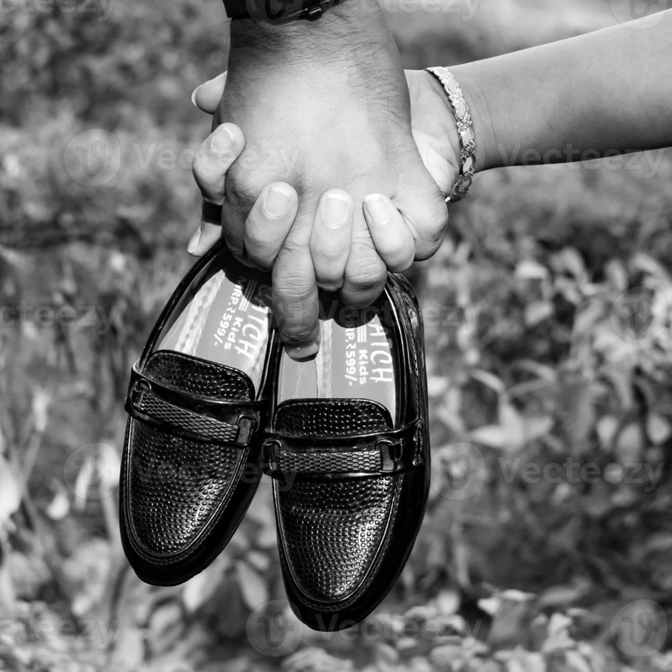 Indian couple posing for maternity baby shoot. The couple is posing in a lawn with green grass and the woman is falunting her baby bump in Lodhi Garden in New Delhi, India - Black and White photo