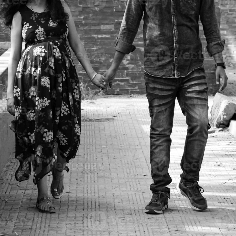 Indian couple posing for maternity baby shoot. The couple is posing in a lawn with green grass and the woman is falunting her baby bump in Lodhi Garden in New Delhi, India - Black and White photo
