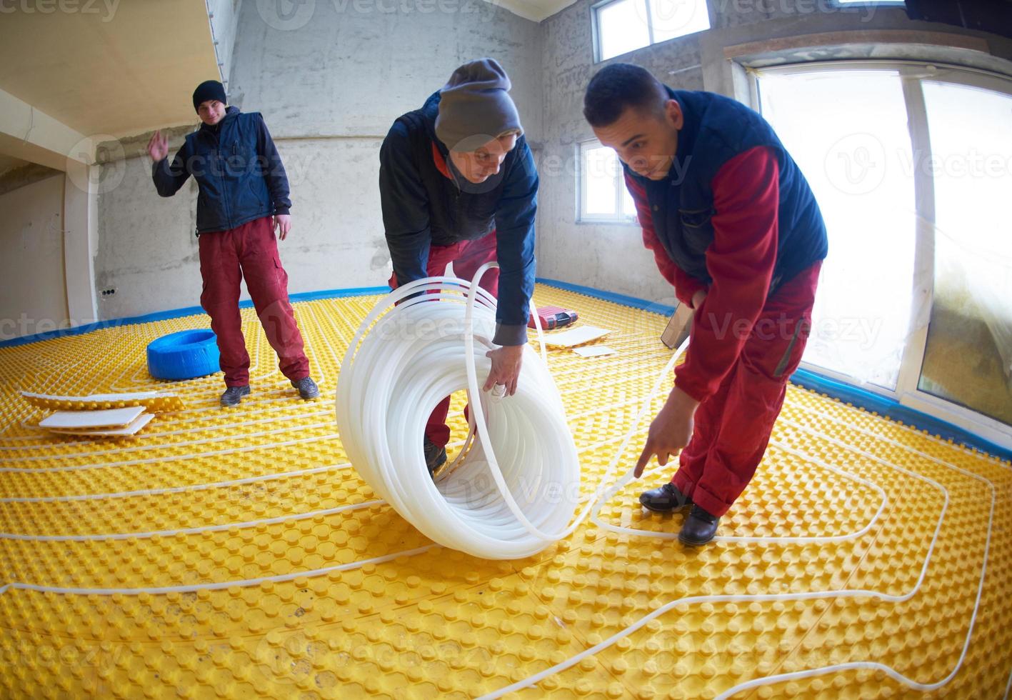 workers installing underfloor heating system photo