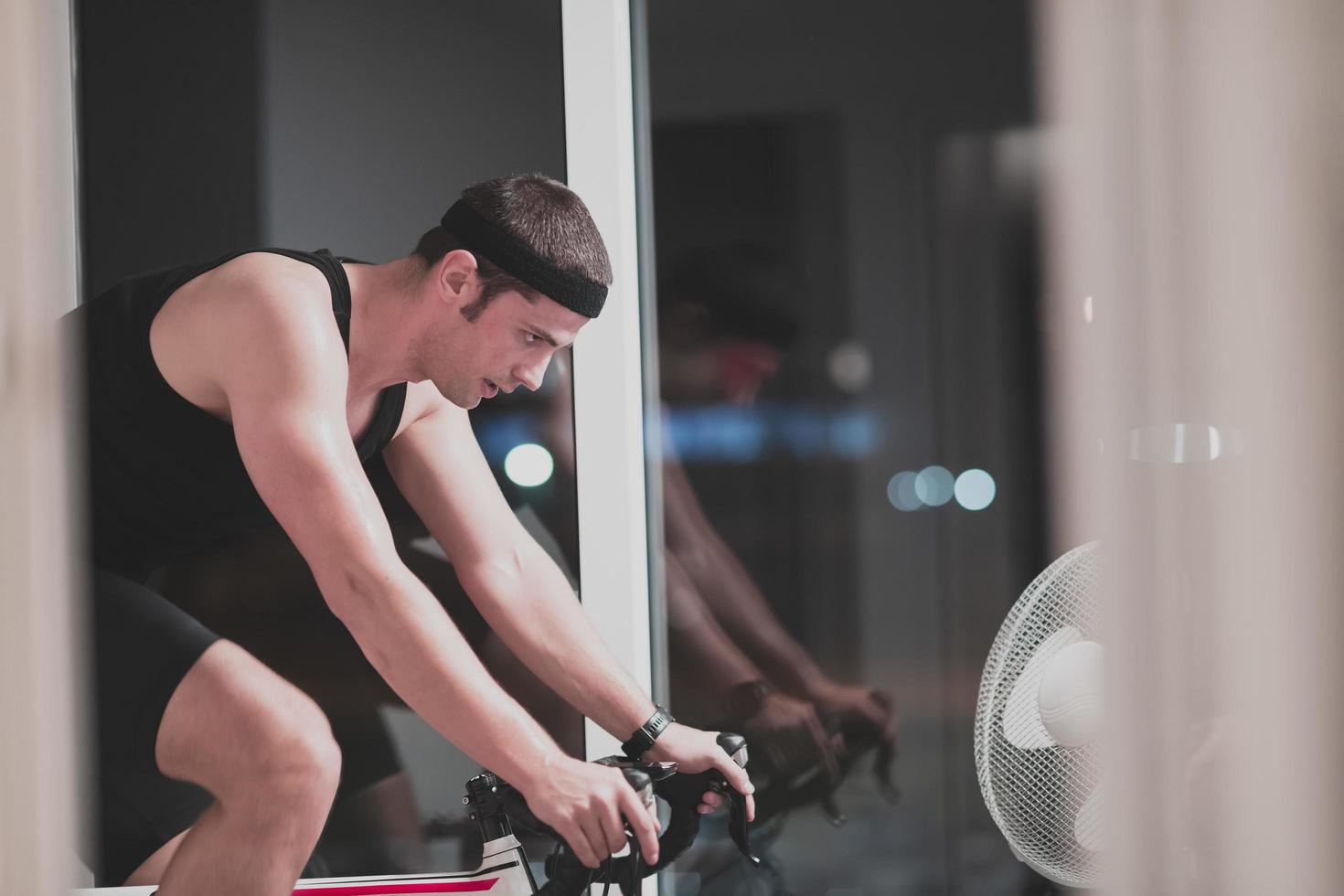 Man cycling on the machine trainer he is exercising in the home at night playing online bike racing game photo