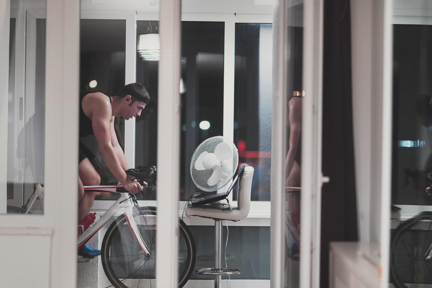 Man cycling on the machine trainer he is exercising in the home at night playing online bike racing game photo