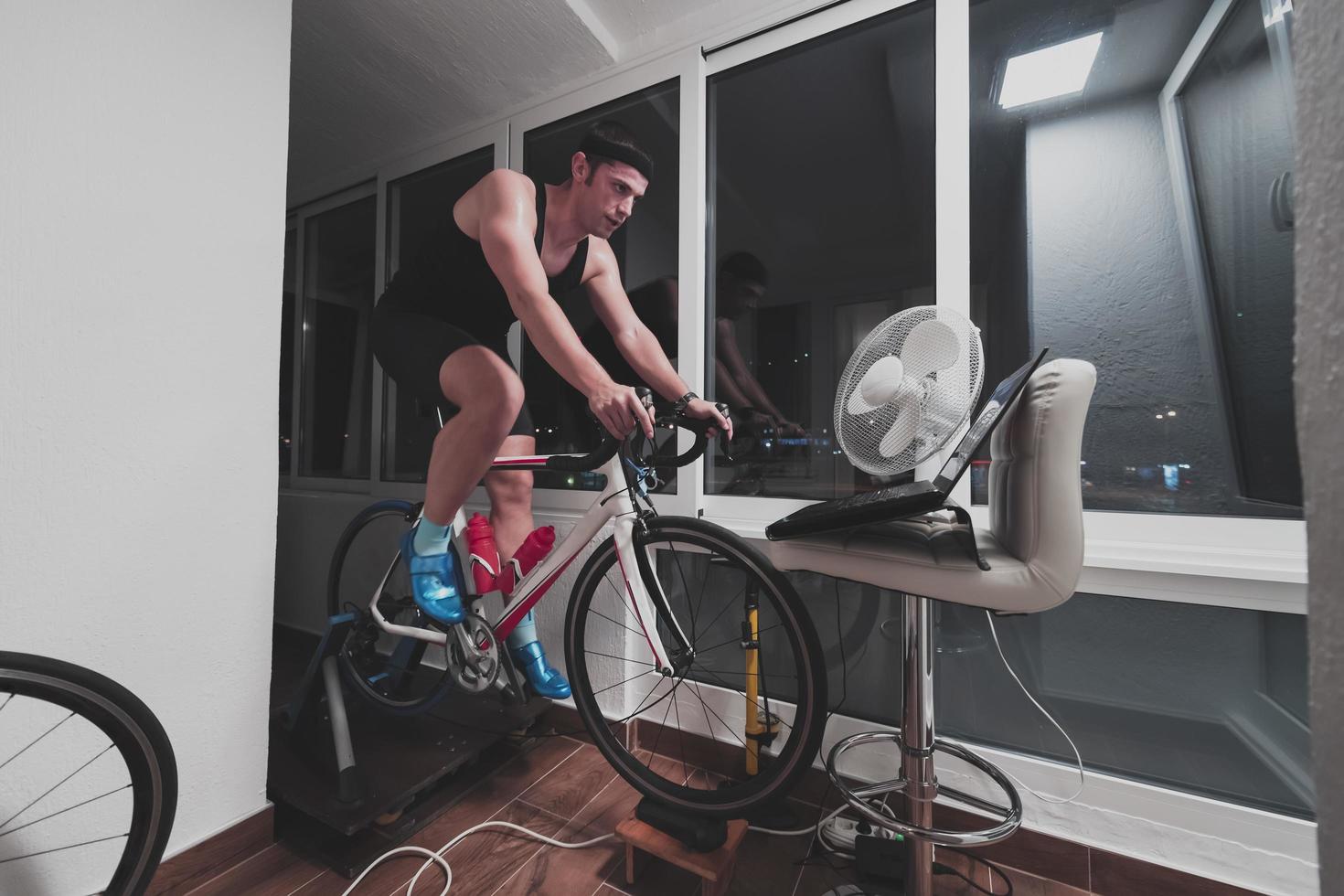 Man cycling on the machine trainer he is exercising in the home at night playing online bike racing game photo