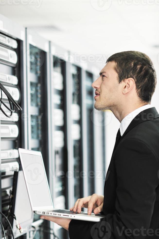 businessman with laptop in network server room photo