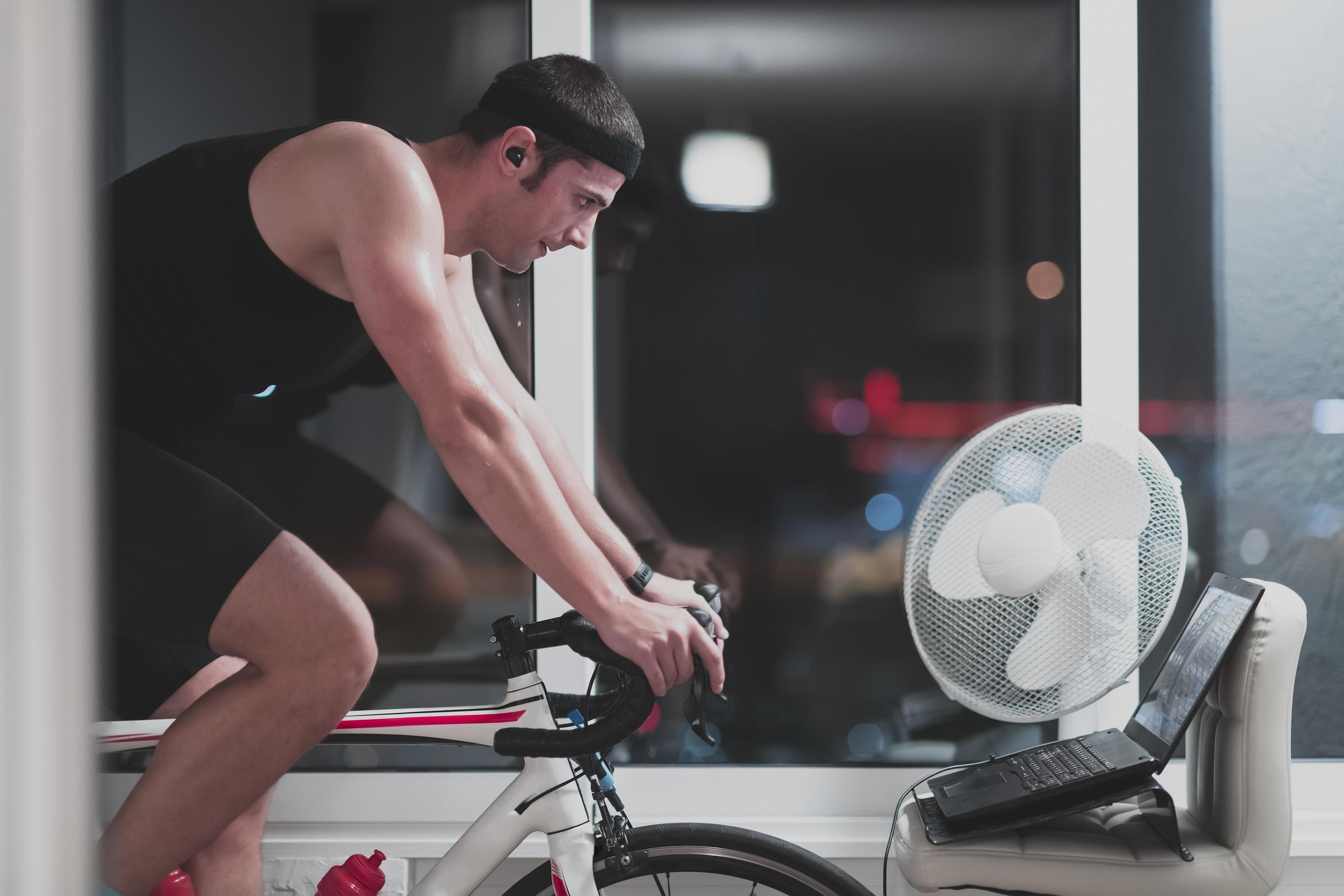 Man cycling on the machine trainer he is exercising in the home at night playing online bike racing game 11576004 Stock Photo at Vecteezy