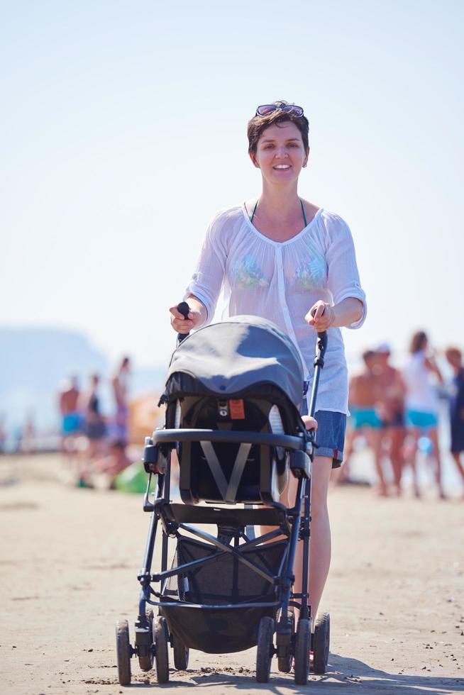 mother walking on beach and push baby carriage photo