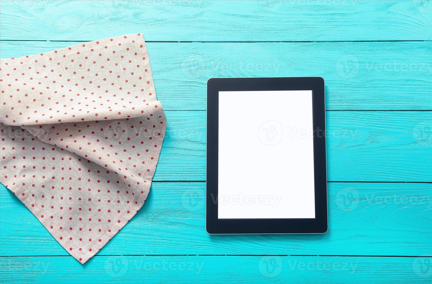 Electronic device with place for text and tablecloth in polka dots on blue wooden background. Top view and copy space. photo