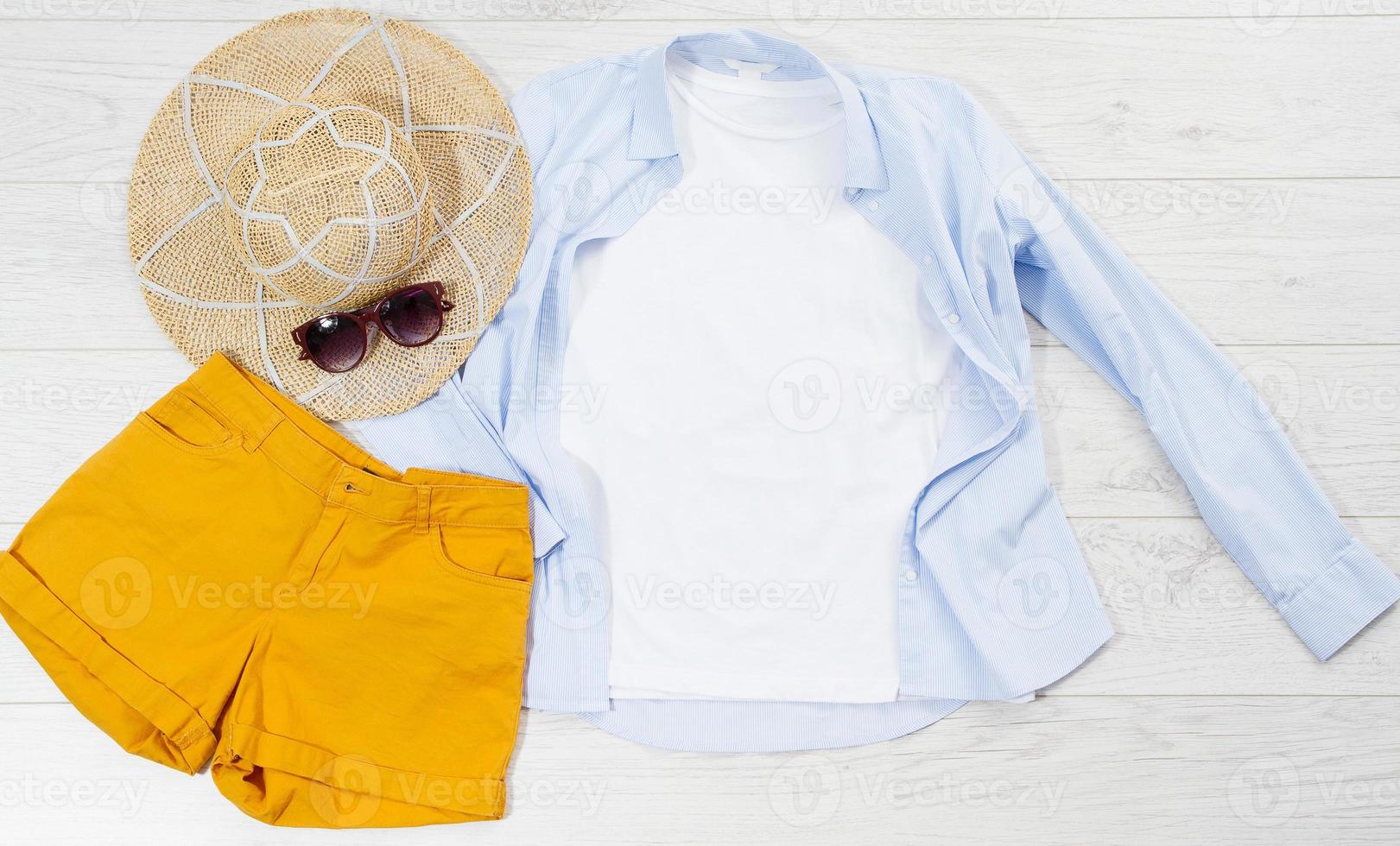 White closeup t shirt mock up flat lay on wooden background. Summer accessories. Hat, sunglasses. Top view and copy space. Mockup t-shirt and summertime. Template blank shirt. photo