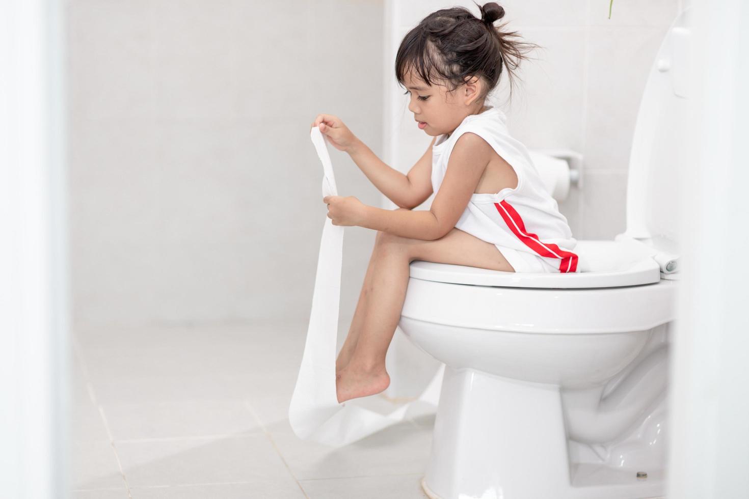 The little girl is sitting on the toilet suffering from constipation or hemorrhoid. photo