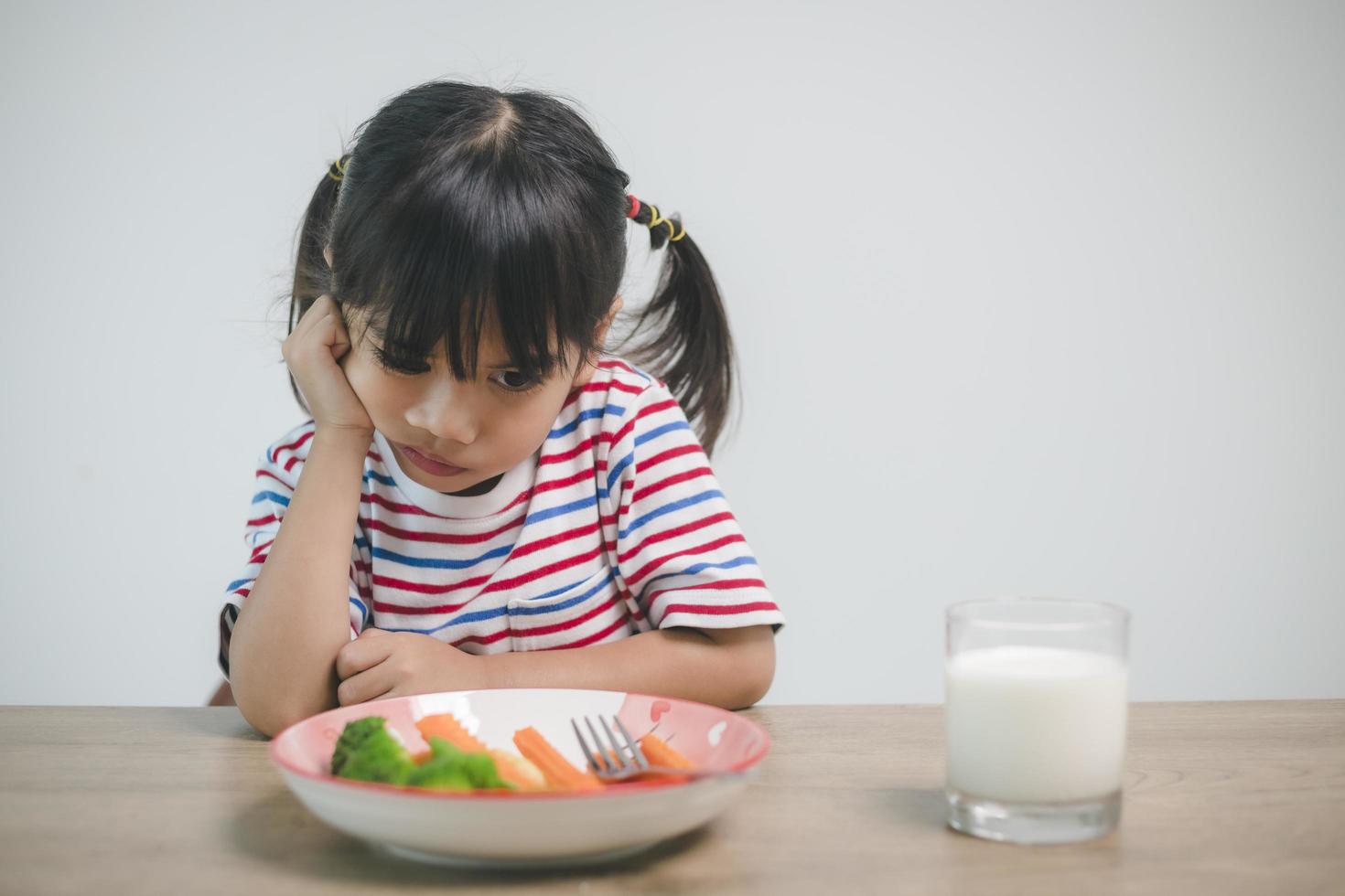 nutrición hábitos alimenticios saludables para el concepto de niños. A los niños no les gusta comer verduras. niña linda se niega a comer verduras saludables. foto