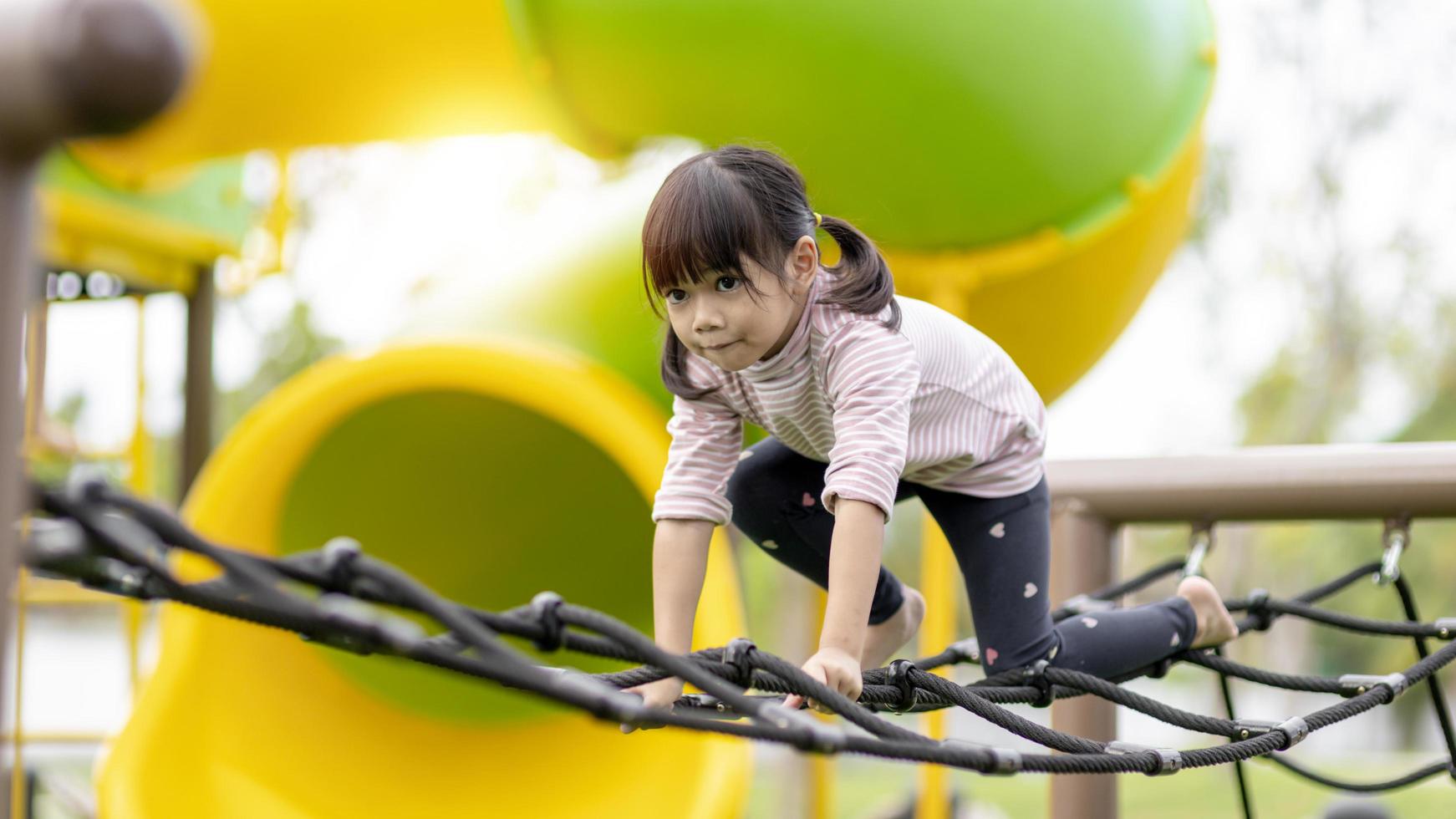 Asian little girl enjoys playing in a children playground, Outdoor portrait photo