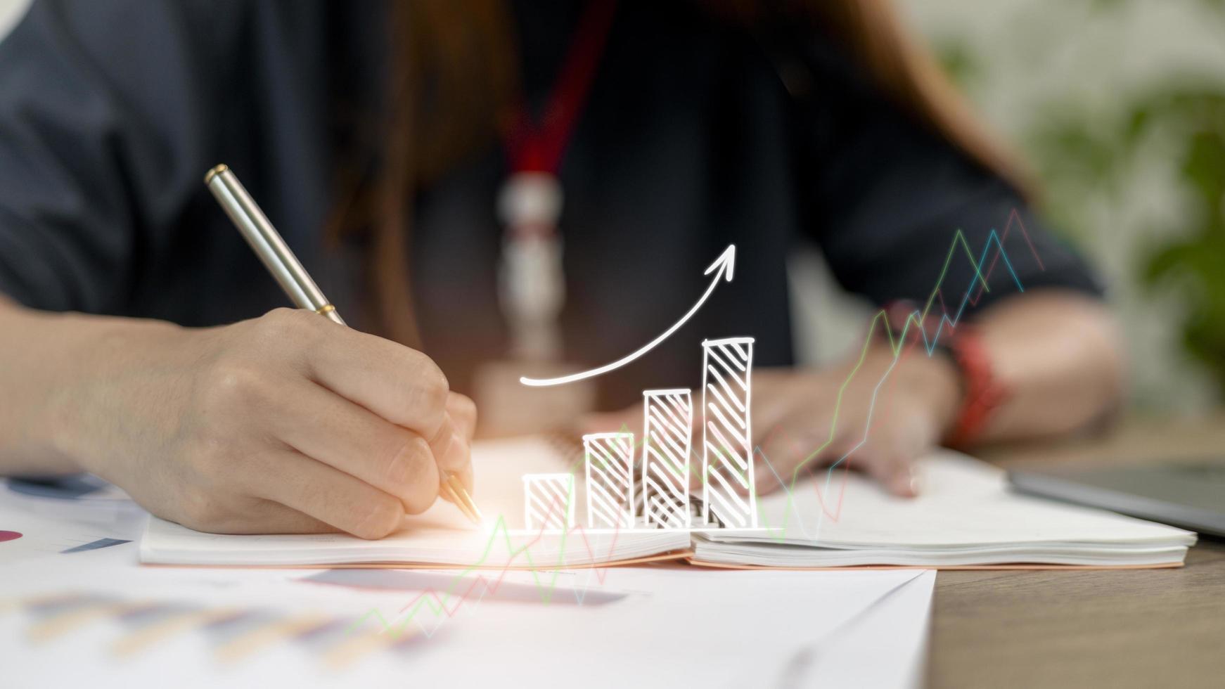 Businesswoman draws an increasing trend arrow and a rising chart from plan to goal. It is a representation of the idea of corporate investment development. photo