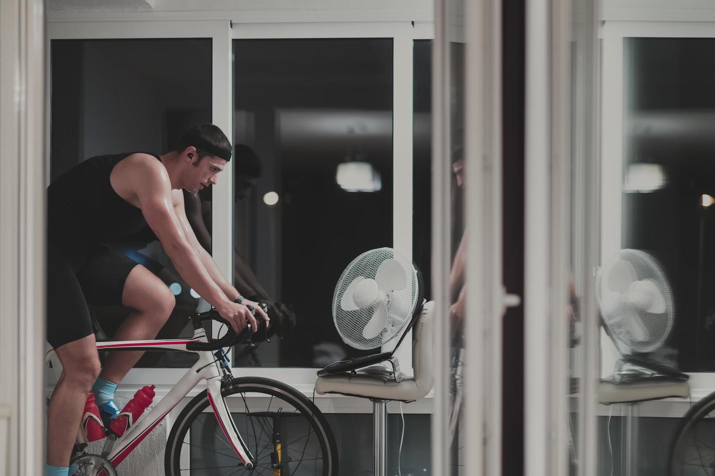 Man cycling on the machine trainer he is exercising in the home at night playing online bike racing game photo