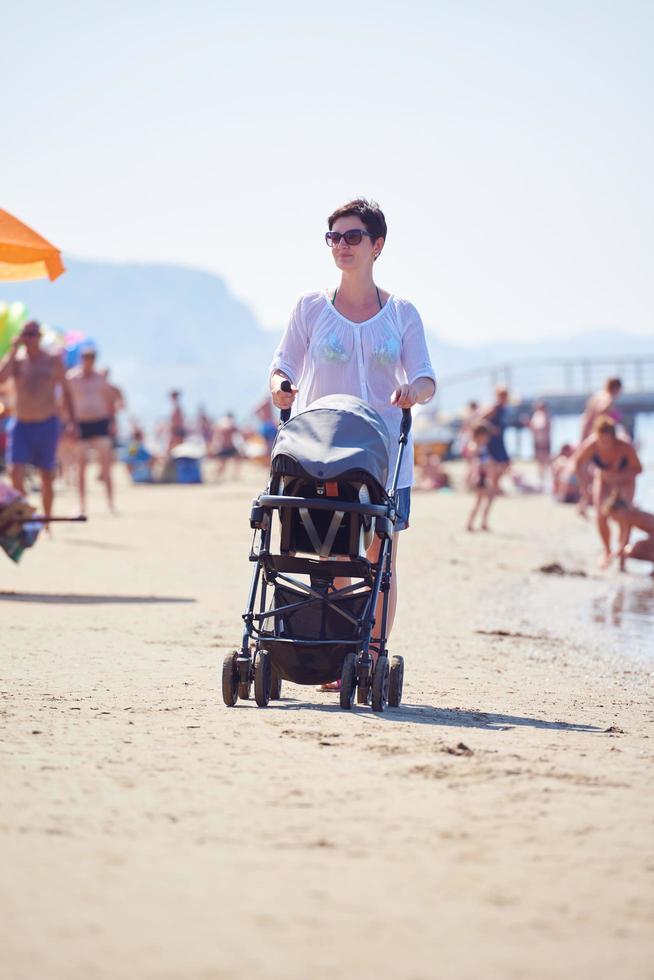 mother walking on beach and push baby carriage photo