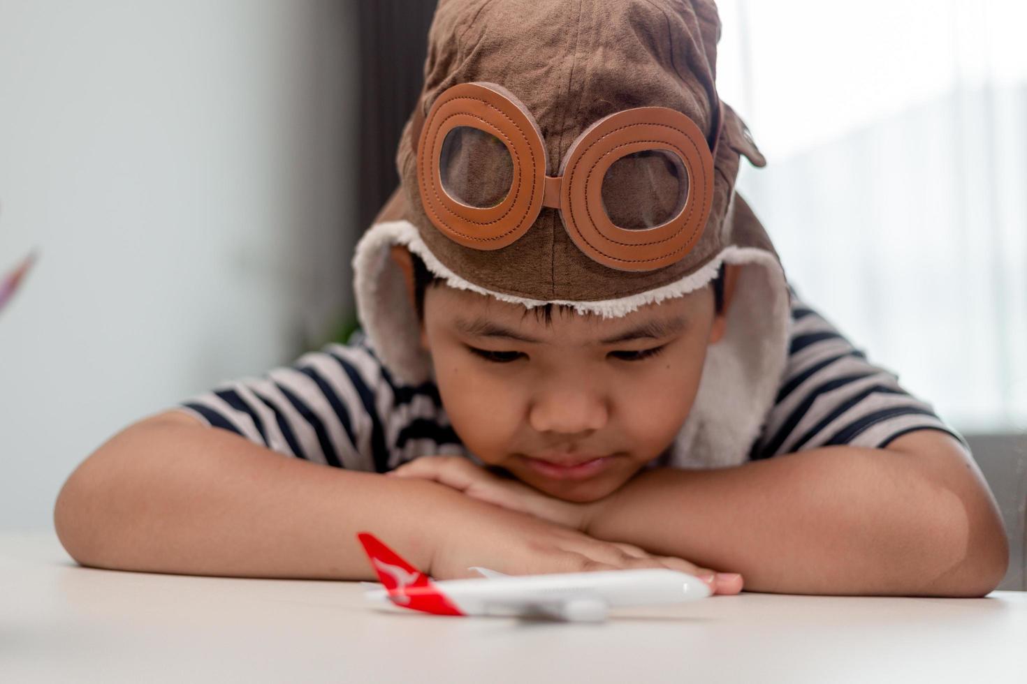 niño pequeño con avión de madera, el niño quiere convertirse en piloto y astronauta. niño feliz jugar con avión de juguete. los niños pilotos sueñan con volar. cara de niños lindos. foto