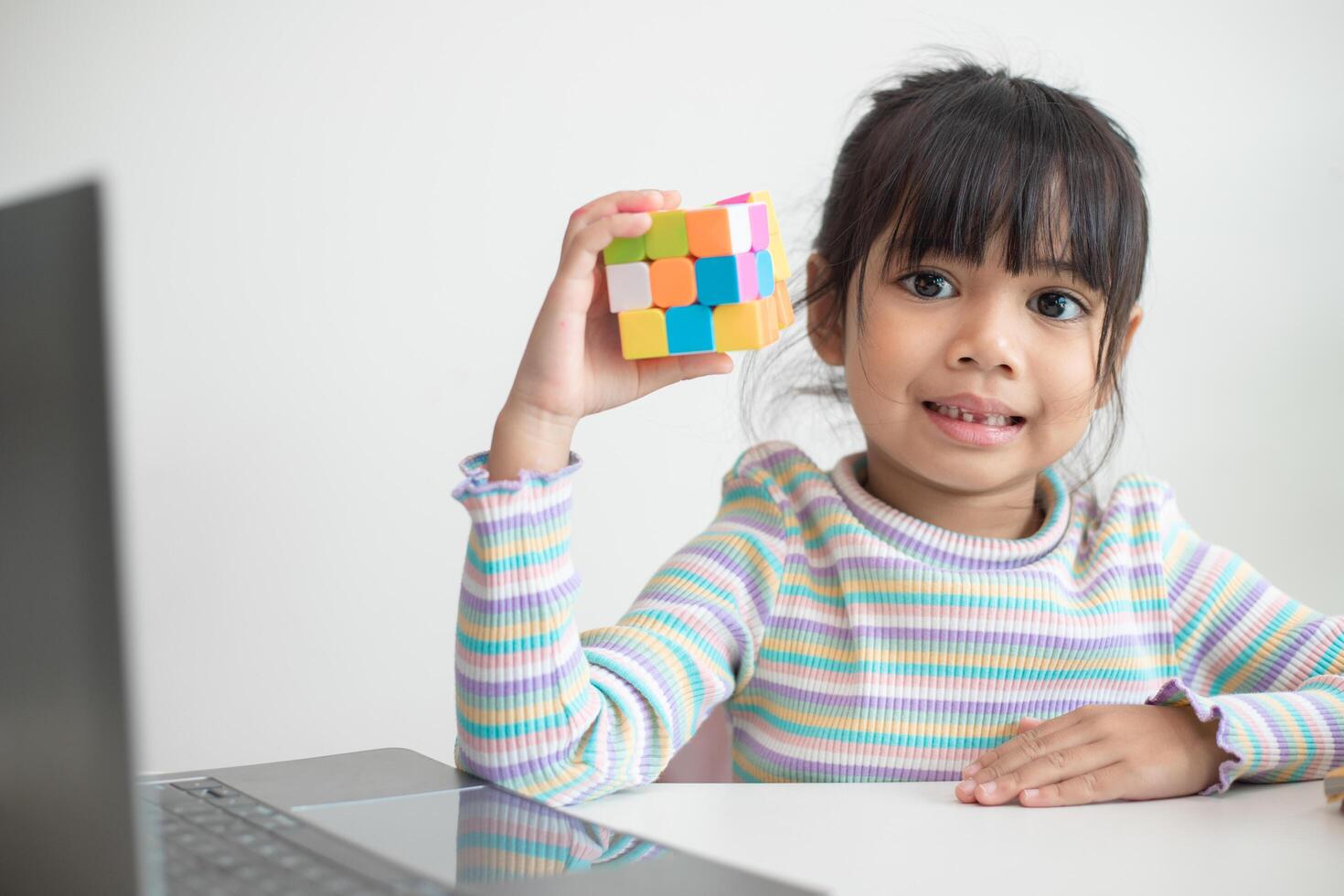 linda niña asiática sosteniendo el cubo de rubik en sus manos. el cubo de rubik es un juego que aumenta la inteligencia de los niños. foto