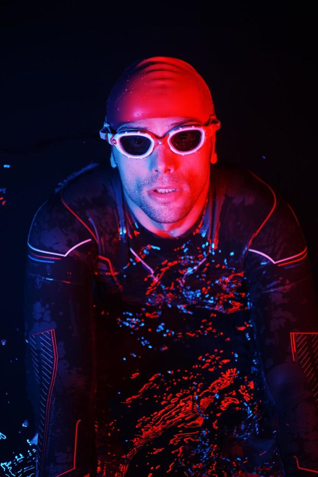 authentic triathlete swimmer having a break during hard training on night neon gel light photo