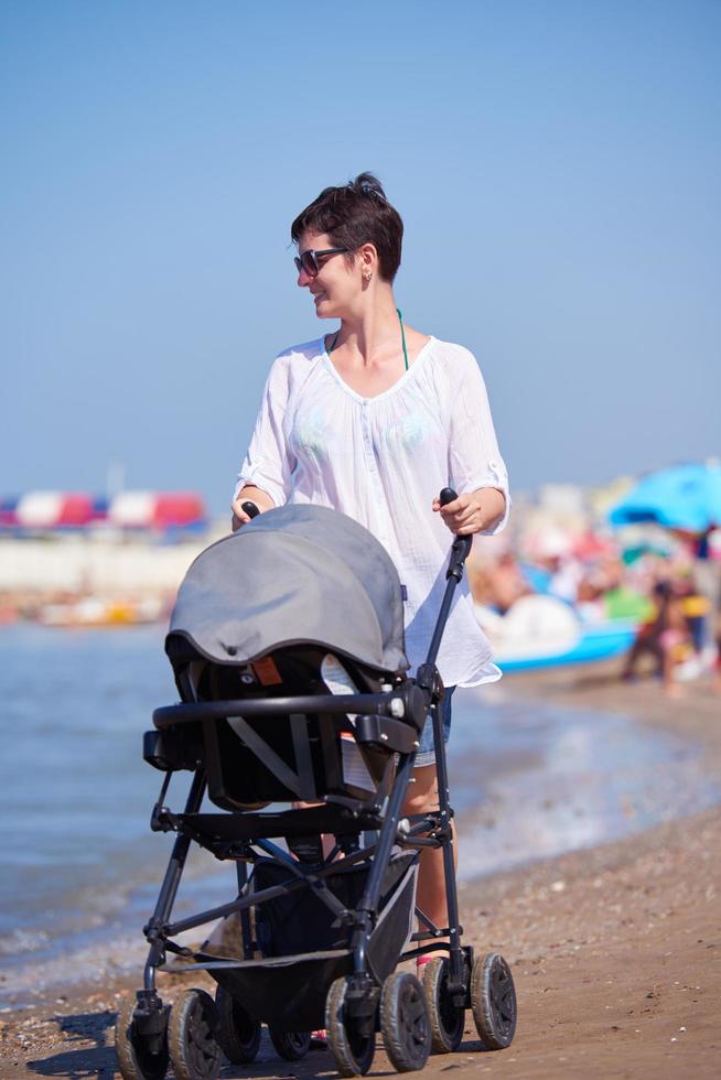 mother walking on beach and push baby carriage photo