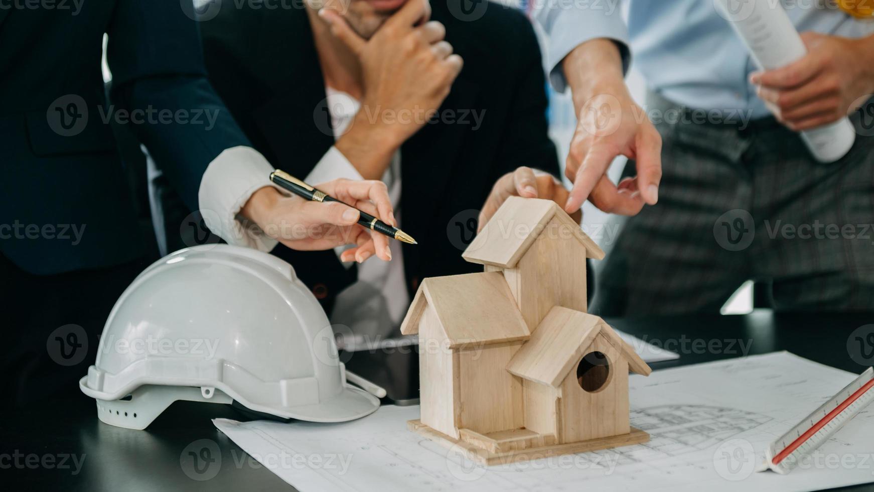 Close up shot of scale model house on table with architects. Two architects making architectural model in office together. to form a new buildin photo