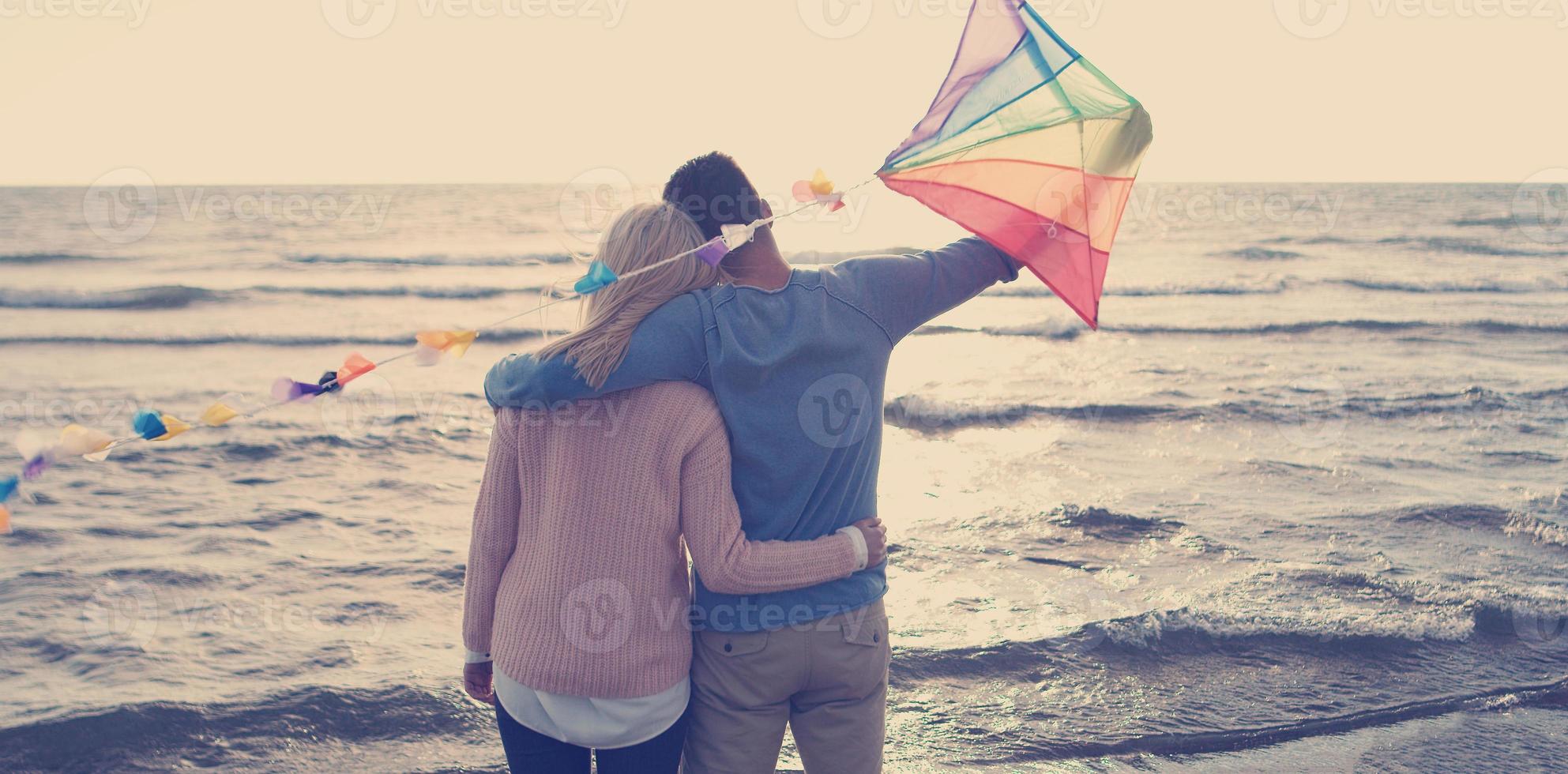 Happy couple having fun with kite on beach photo