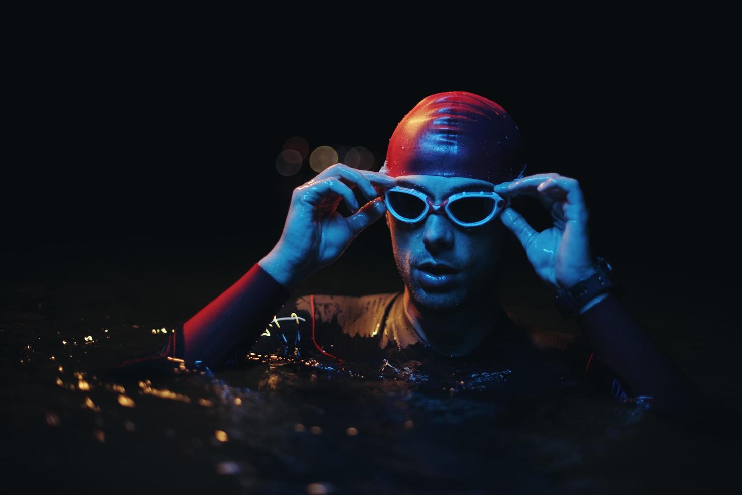 nadador triatleta auténtico que tiene un descanso durante el entrenamiento duro en la luz de gel de neón nocturno foto