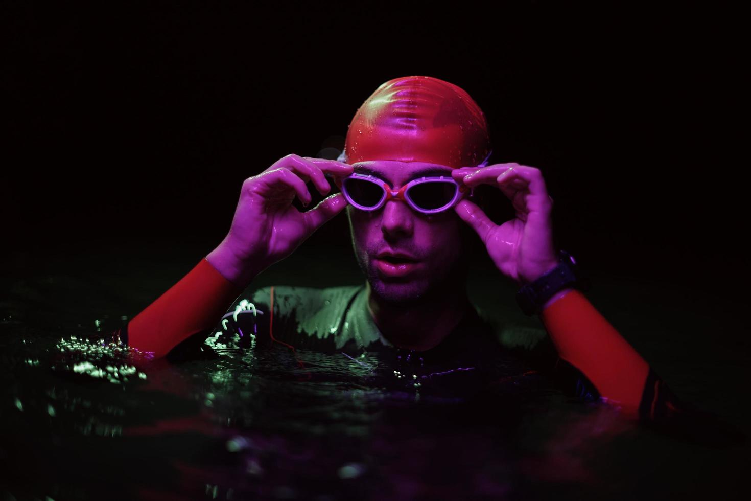 authentic triathlete swimmer having a break during hard training on night neon gel light photo