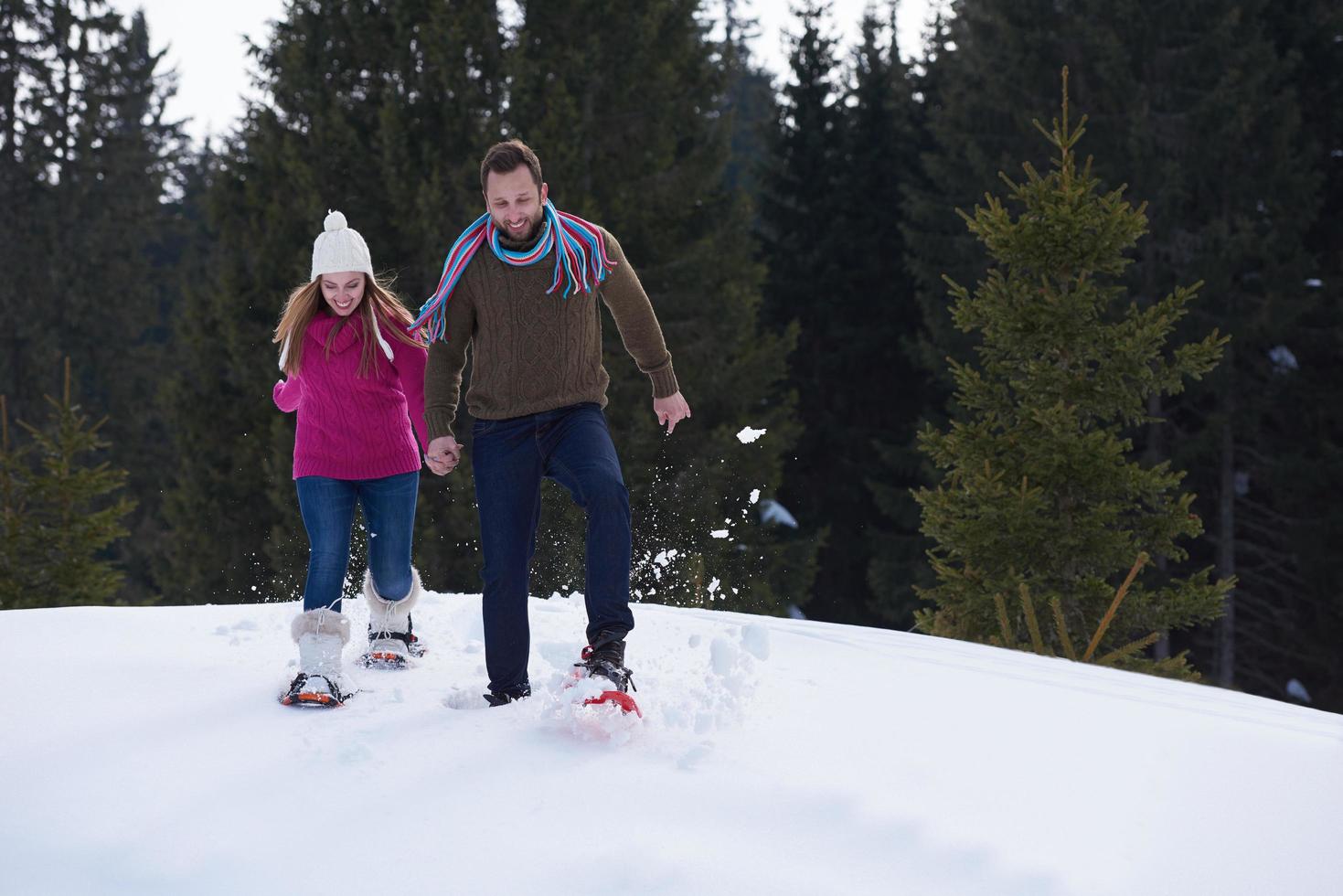 couple having fun and walking in snow shoes photo