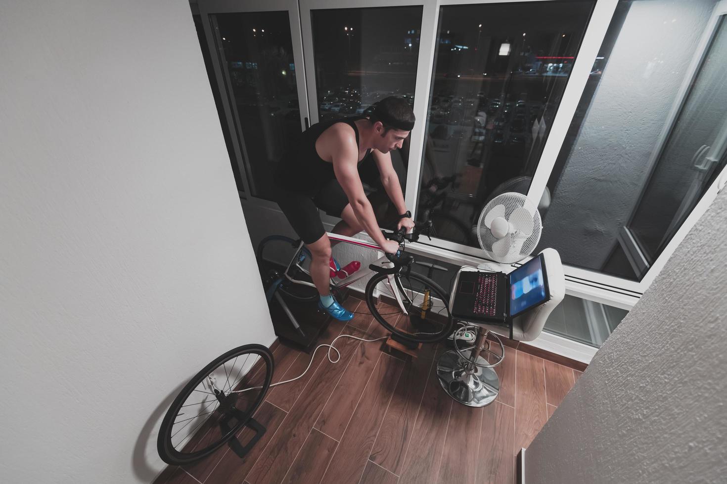 Man cycling on the machine trainer he is exercising in the home at night playing online bike racing game photo