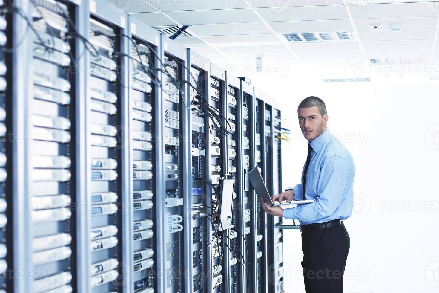 businessman with laptop in network server room photo